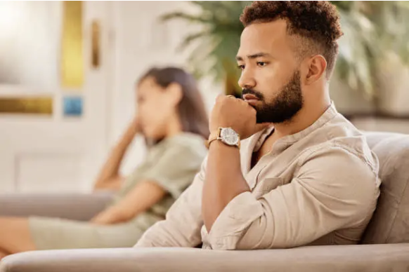 A man and a woman sitting on a couch in couples therapy.