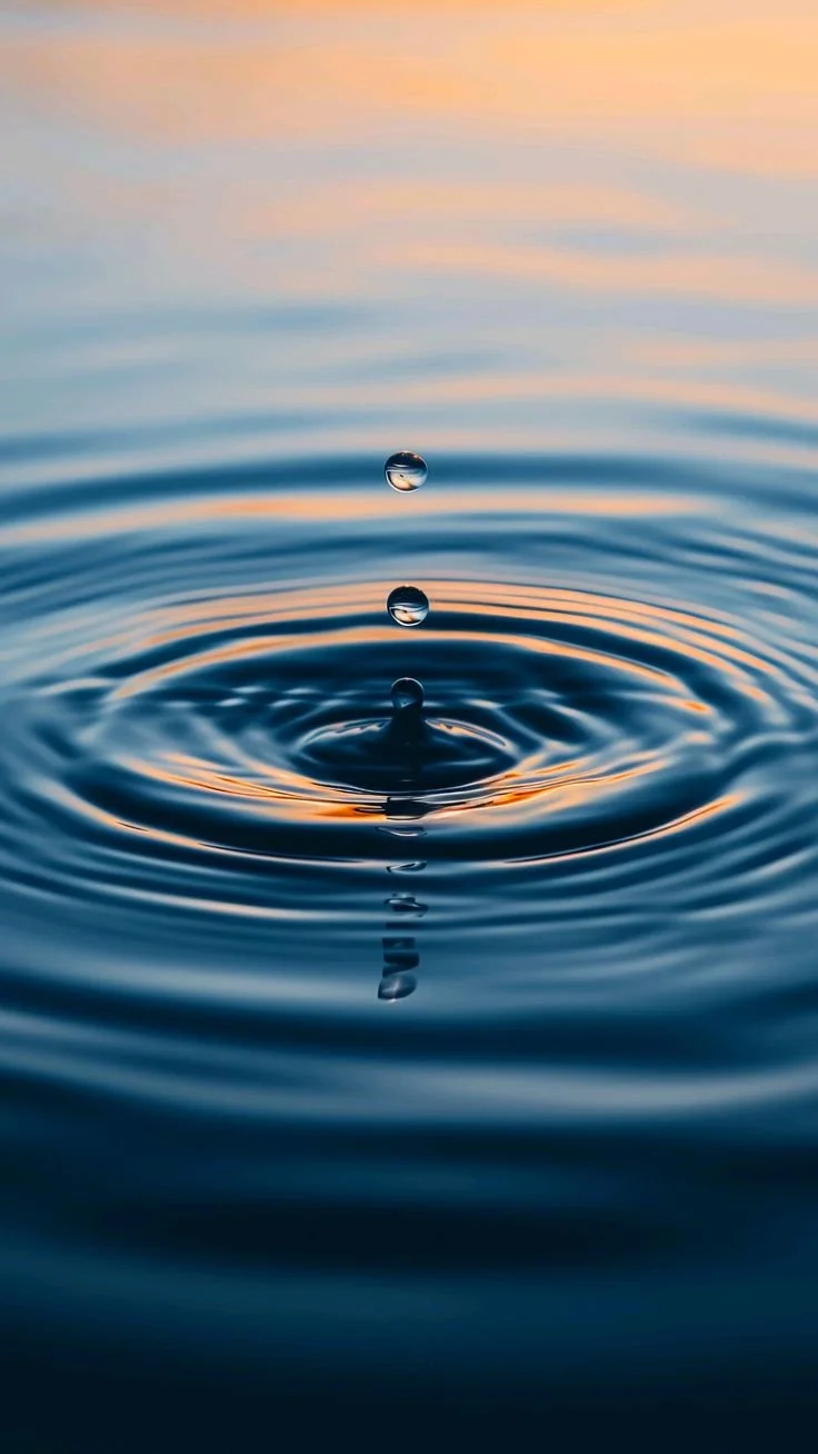Close-up of water droplets falling into a body of water, creating ripples. The background is split diagonally with yellow on the top left and blue on the bottom right.