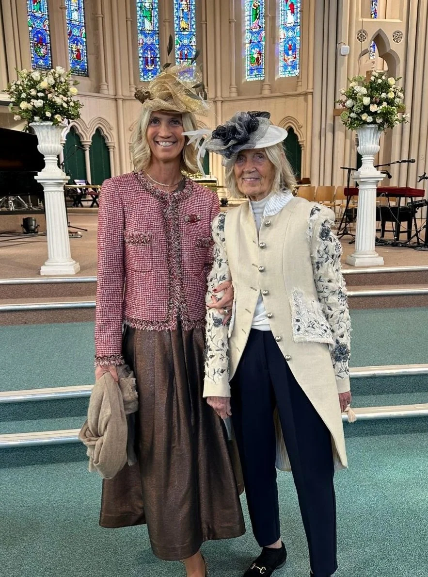 A very elegant mother and daughter at a special wedding day wearing complimentary saucer style hats.