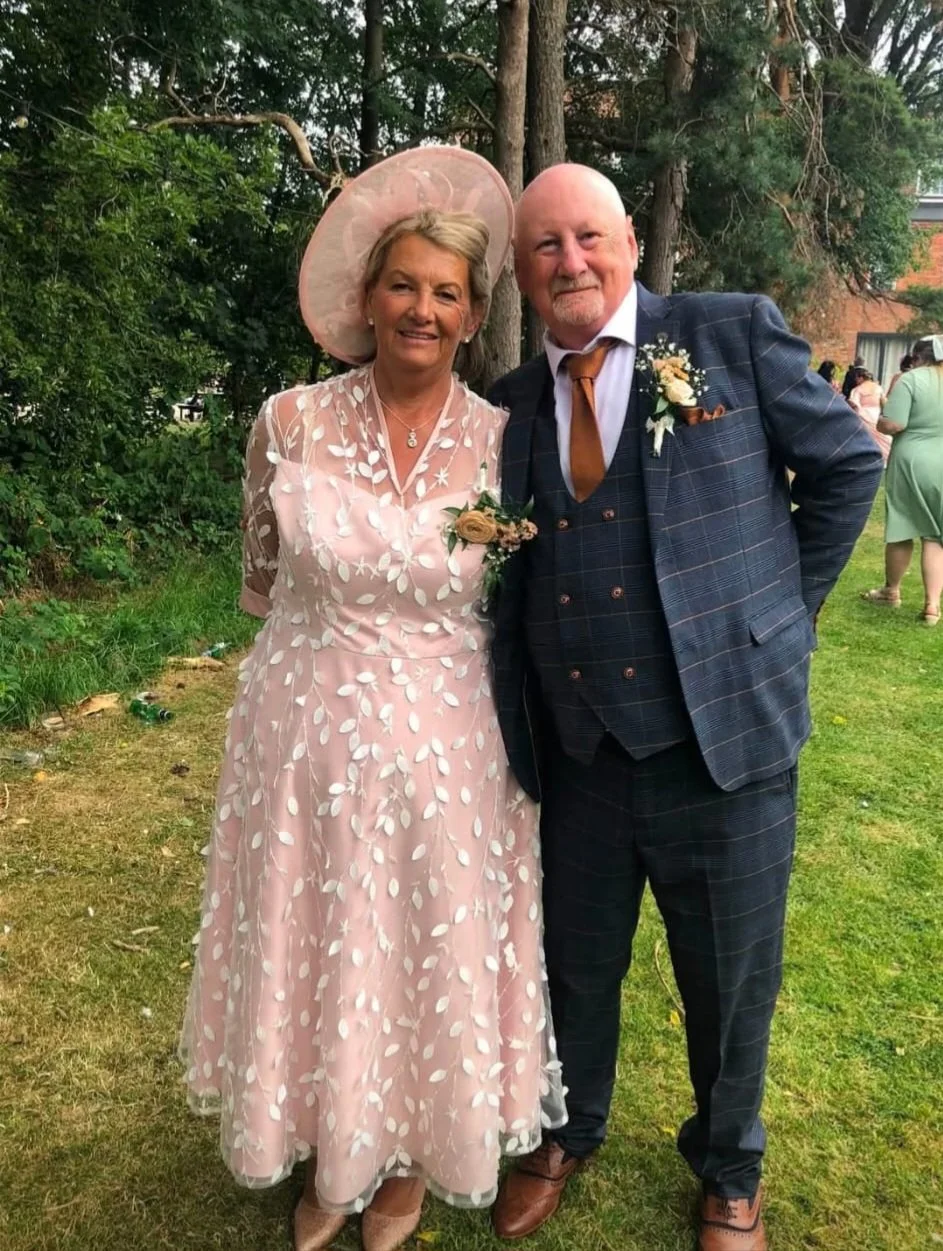 A fantastic mother of the bridge, alongside her dashing husband, a perfect colour match from hat to dress.