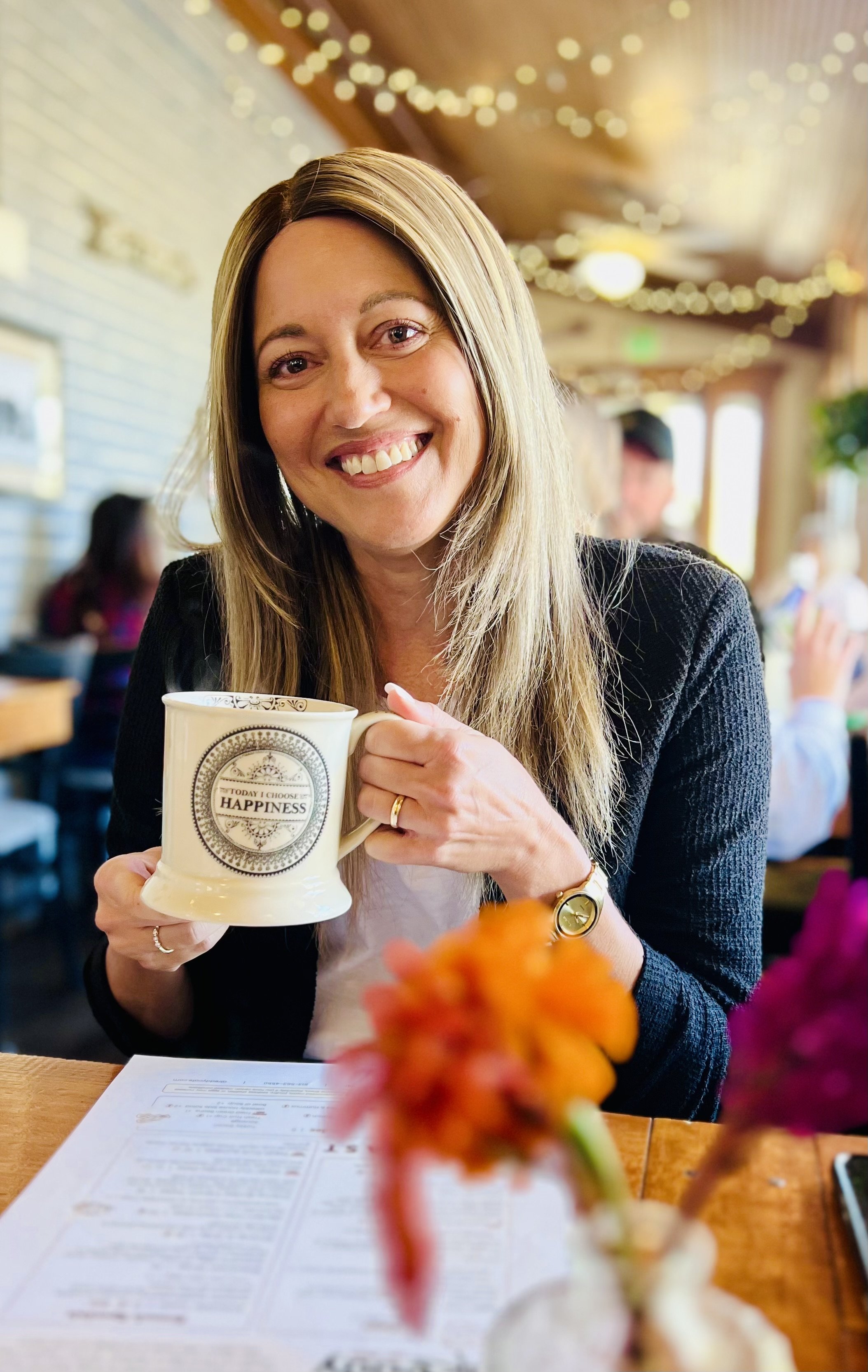 Author Julie Yost smiling with mug at a coffee shop.