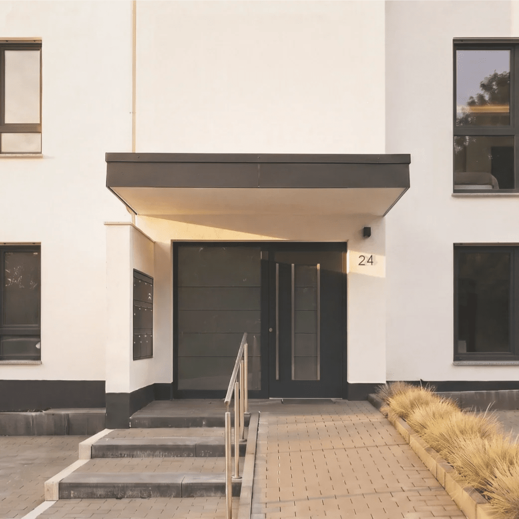 Barrierefreier Eingang zum Mehrfamilienhaus "an der mehrzweckhalle" mit Treppen- und Rampenanlage in minimalistischem Stil.
