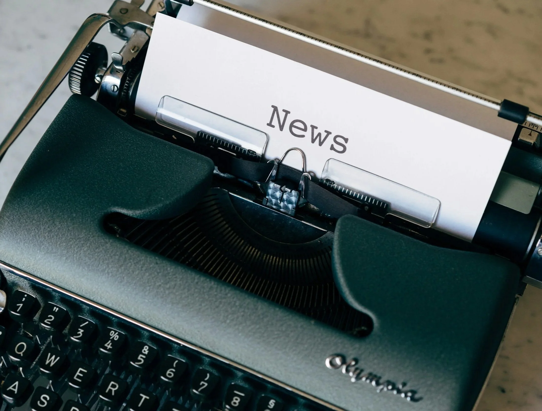 Close-up of a vintage typewriter with a paper that says 'News' in the carriage.