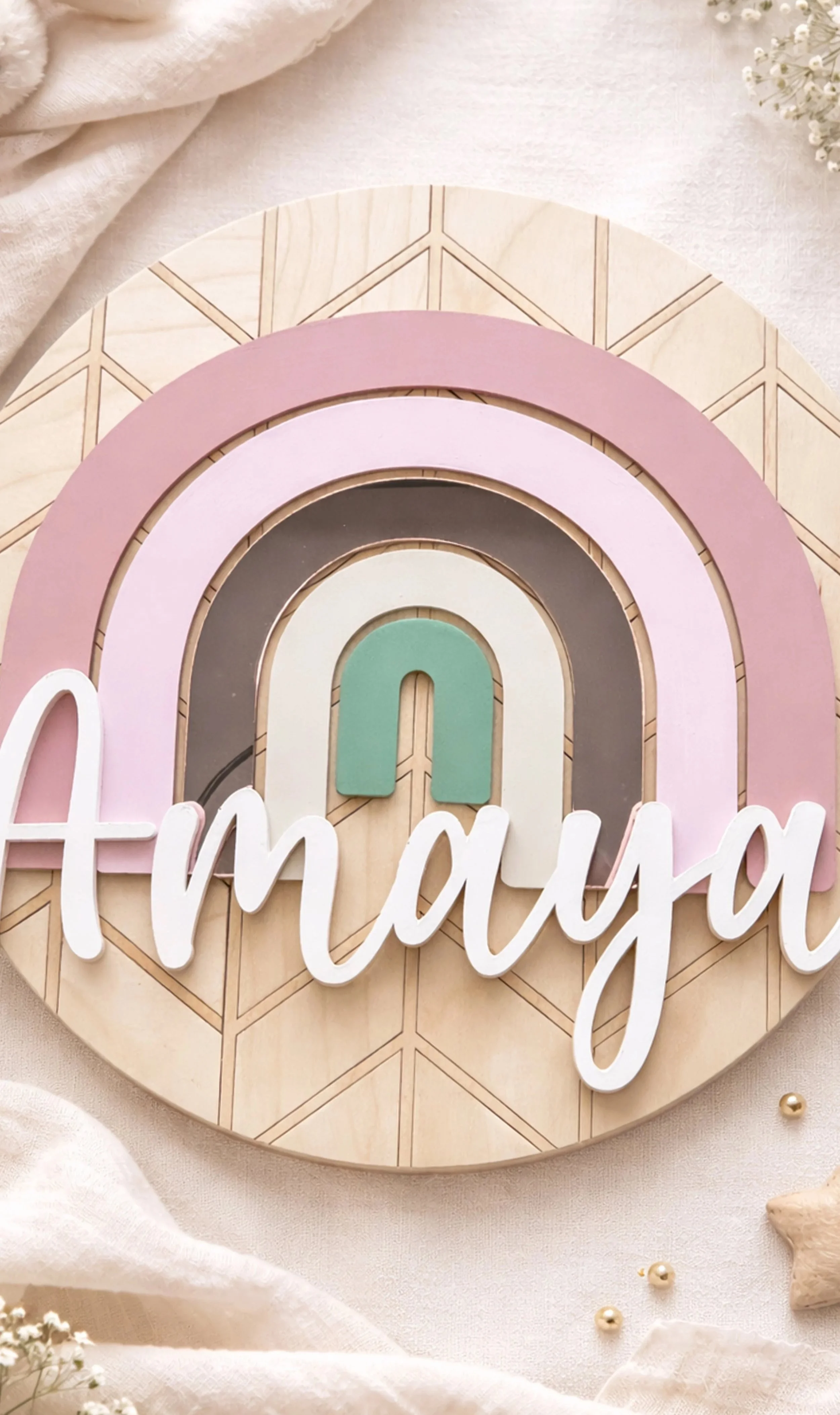 Layered wooden name sign reading “Amaya” with a pastel rainbow and geometric background in soft pink, tan, and green tones.