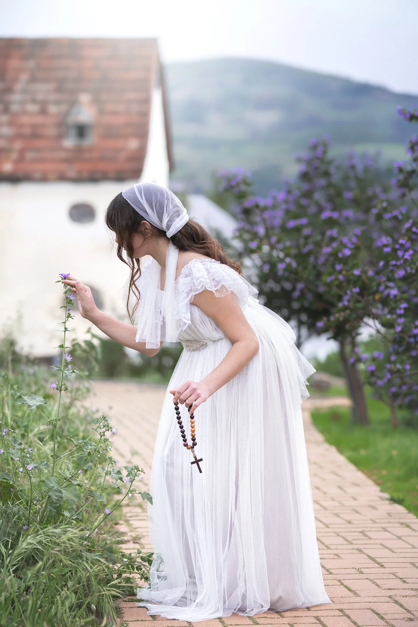 Niña juntando flores en un bosque en Benalmádena vestida de comunión estilo antiguo