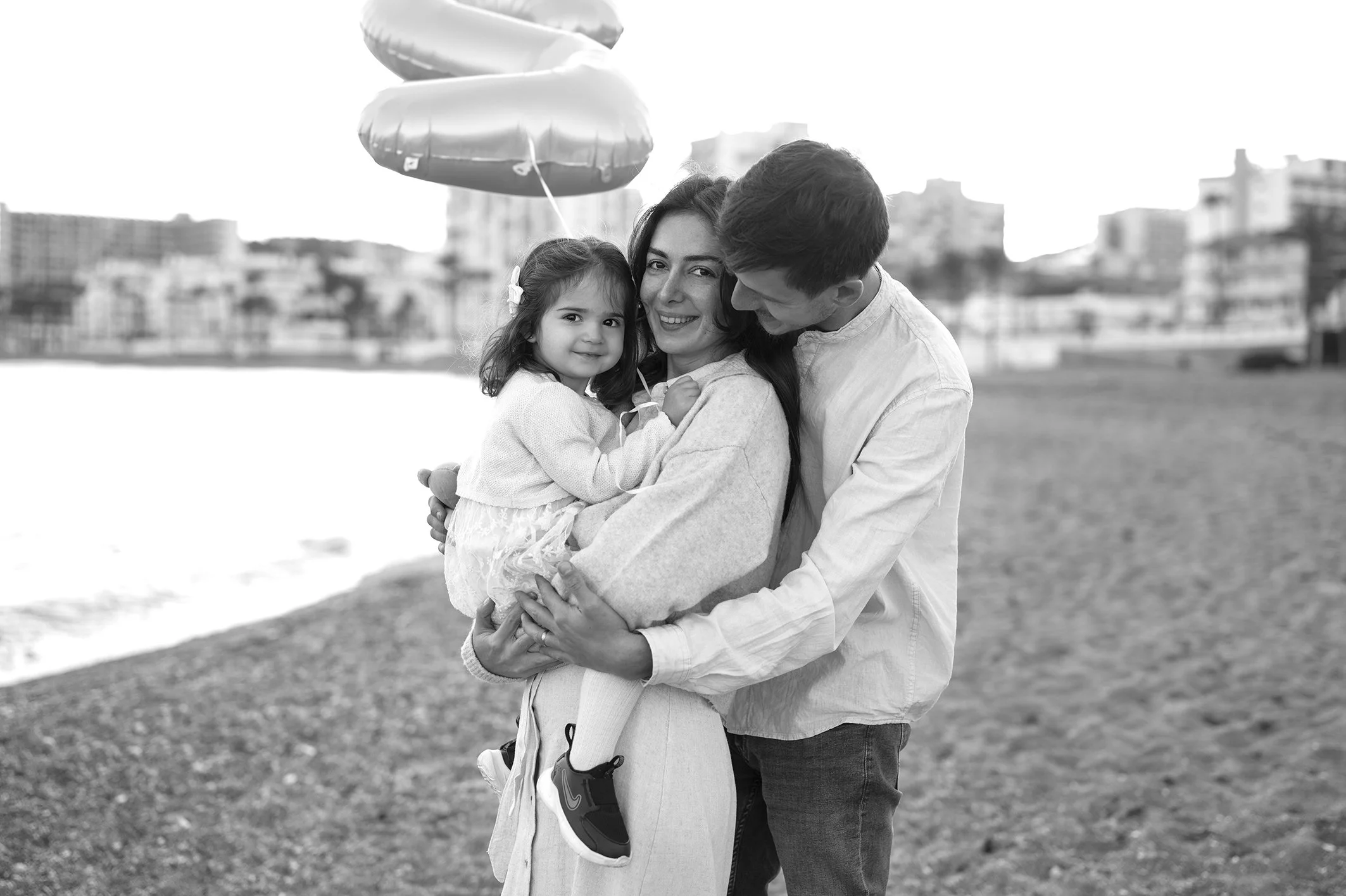 a couple of young people with a little daughter smiling in a photoshoot in Benalmadena beach