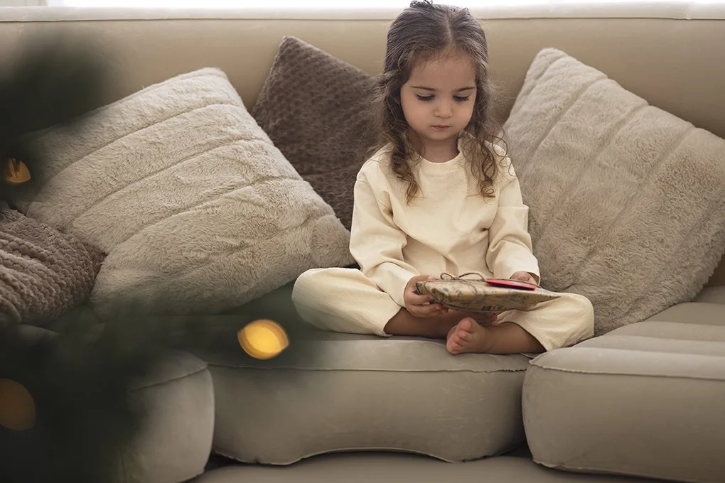 una niña recibiendo un regalo de navidad en el living de su casa