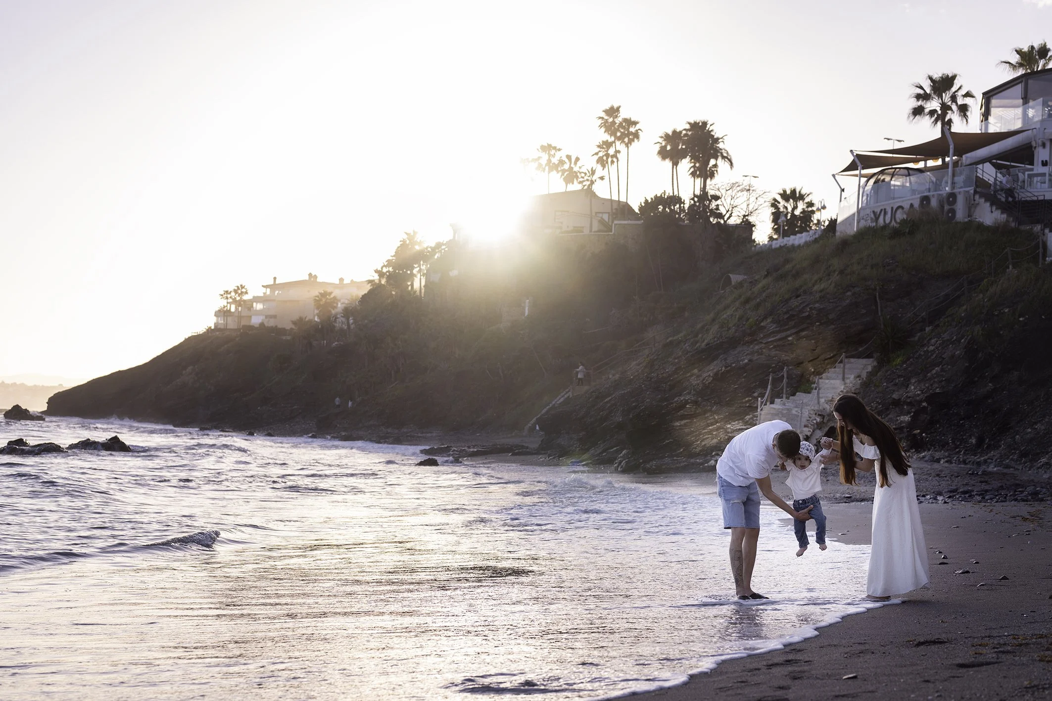 familia caminando a la orilla de la playa en Benalmádena mientras se hacen fotos profesionales