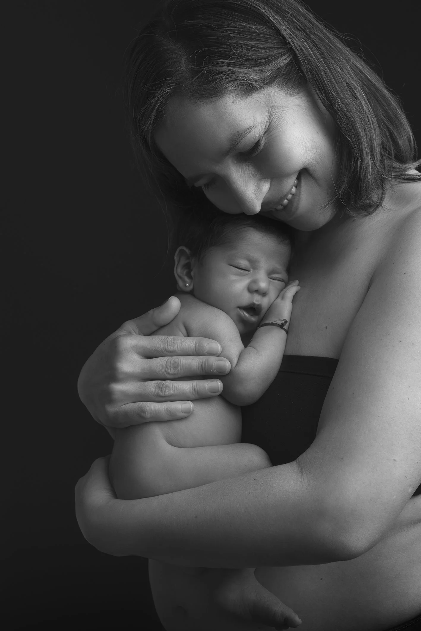 Fotografía profesional en blanco y negro de una madre sosteniendo un bebé recién nacido en una sesión de fotos en estudio en España, Costa del Sol