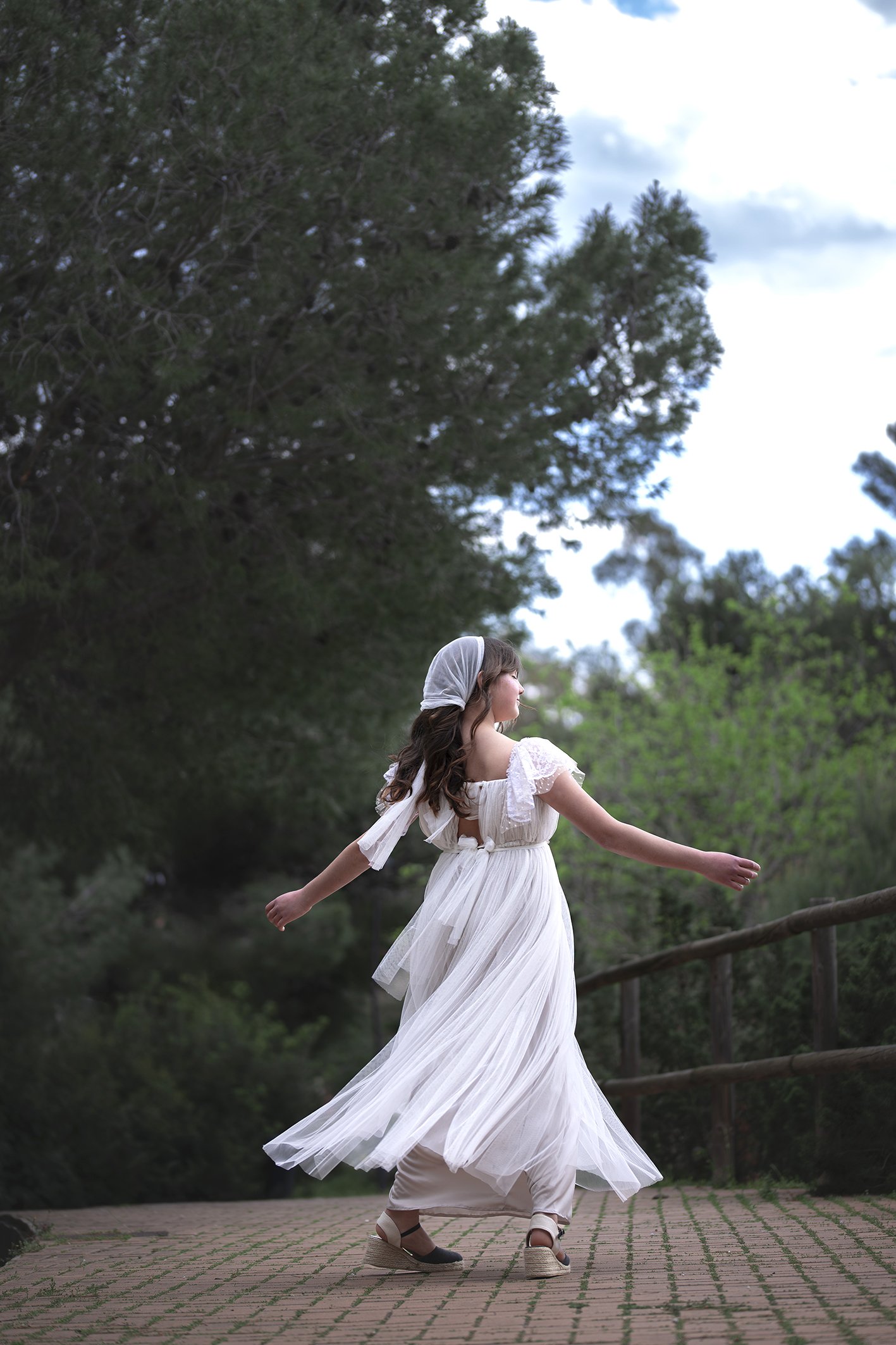 Una niña con una vestido de comunión bailando en un bosque en Benalmádena mientras esta en una sesión de fotos