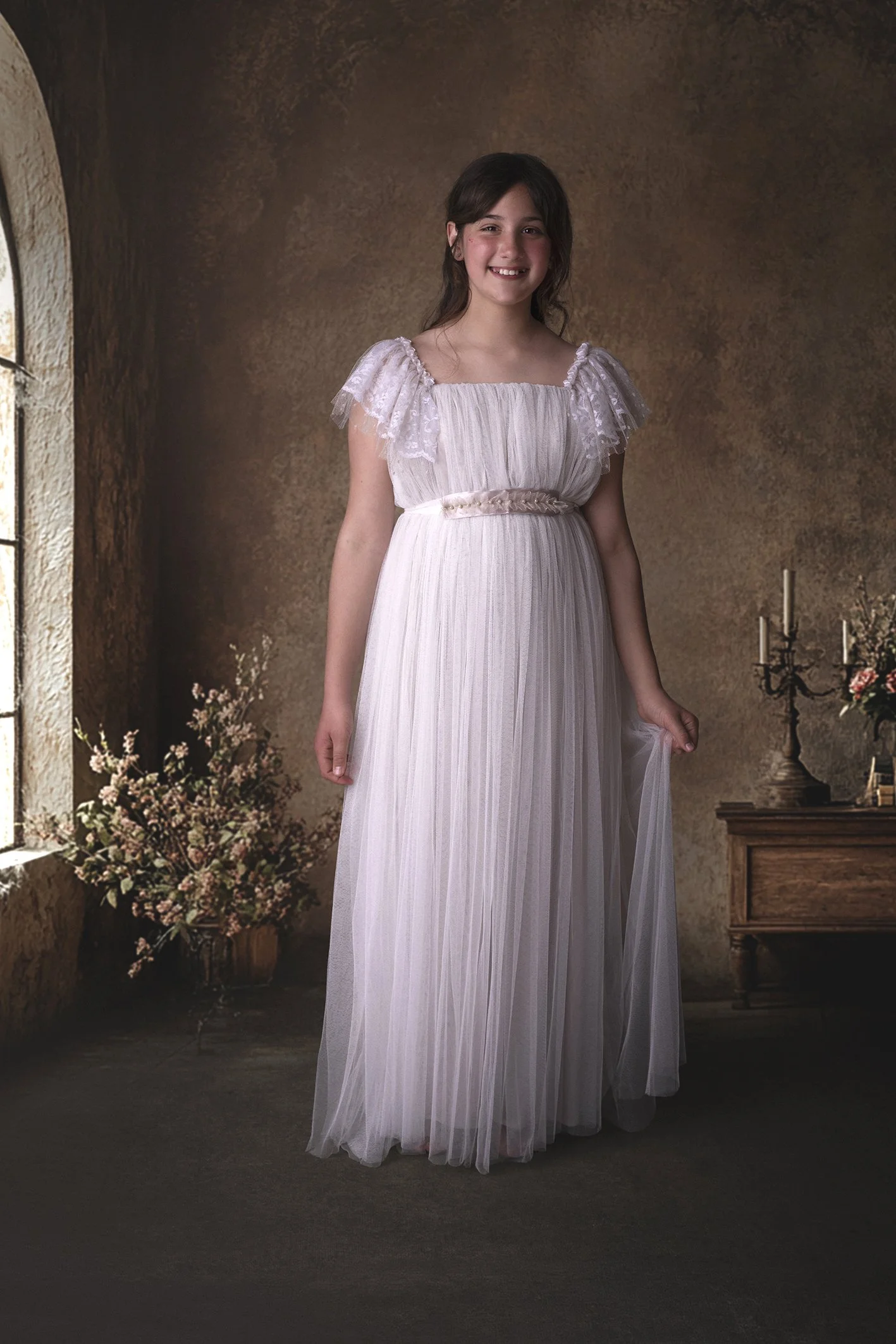 Niña sujetando su vestido de comunión en un estudio profesional de fotografía en Benalmádena 