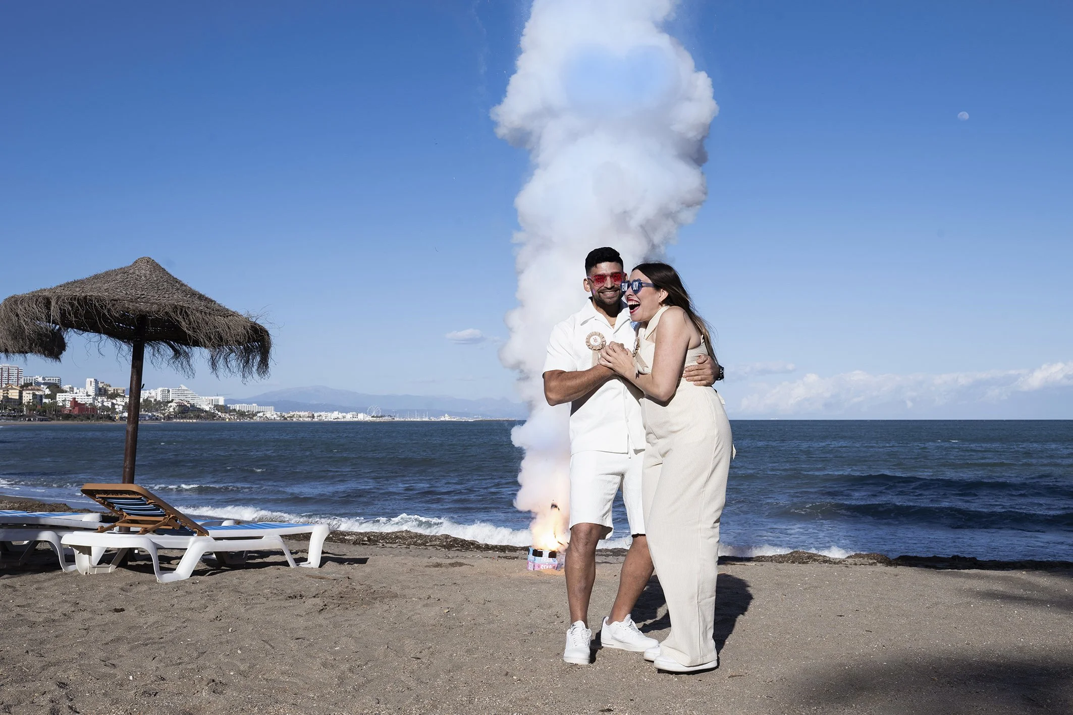 Una pareja muy feliz en la playa, riendo y abrazados, en la playa de Benalmádena lista para una sesión de fotos de revelación de género..