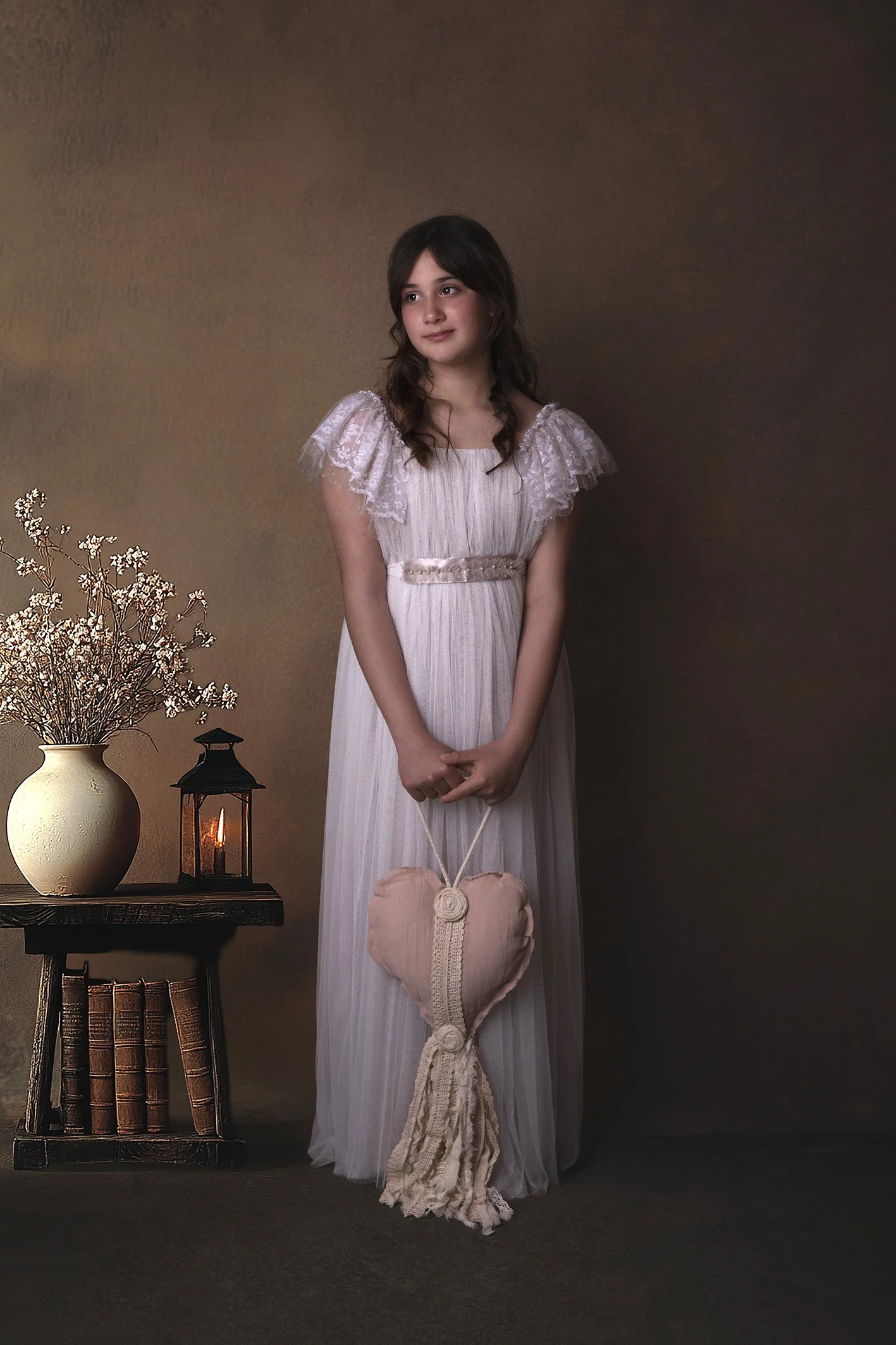 Niña sujetando un corazón de tela vestido de comunión en un estudio profesional de fotografía en Benalmádena 