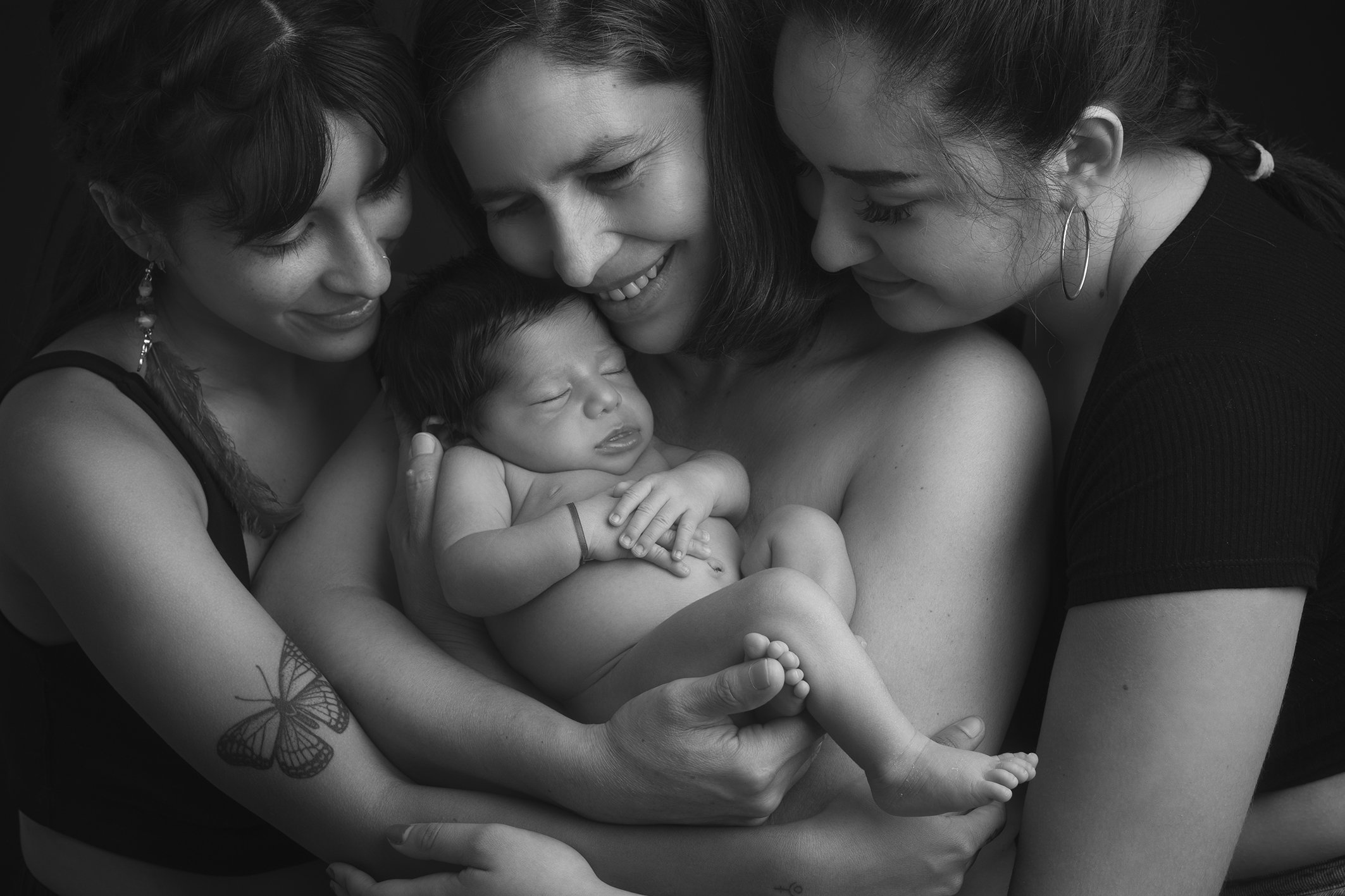 familia feliz abrazando a bebé recién nacido en una sesión de fotos en estudio en Málaga