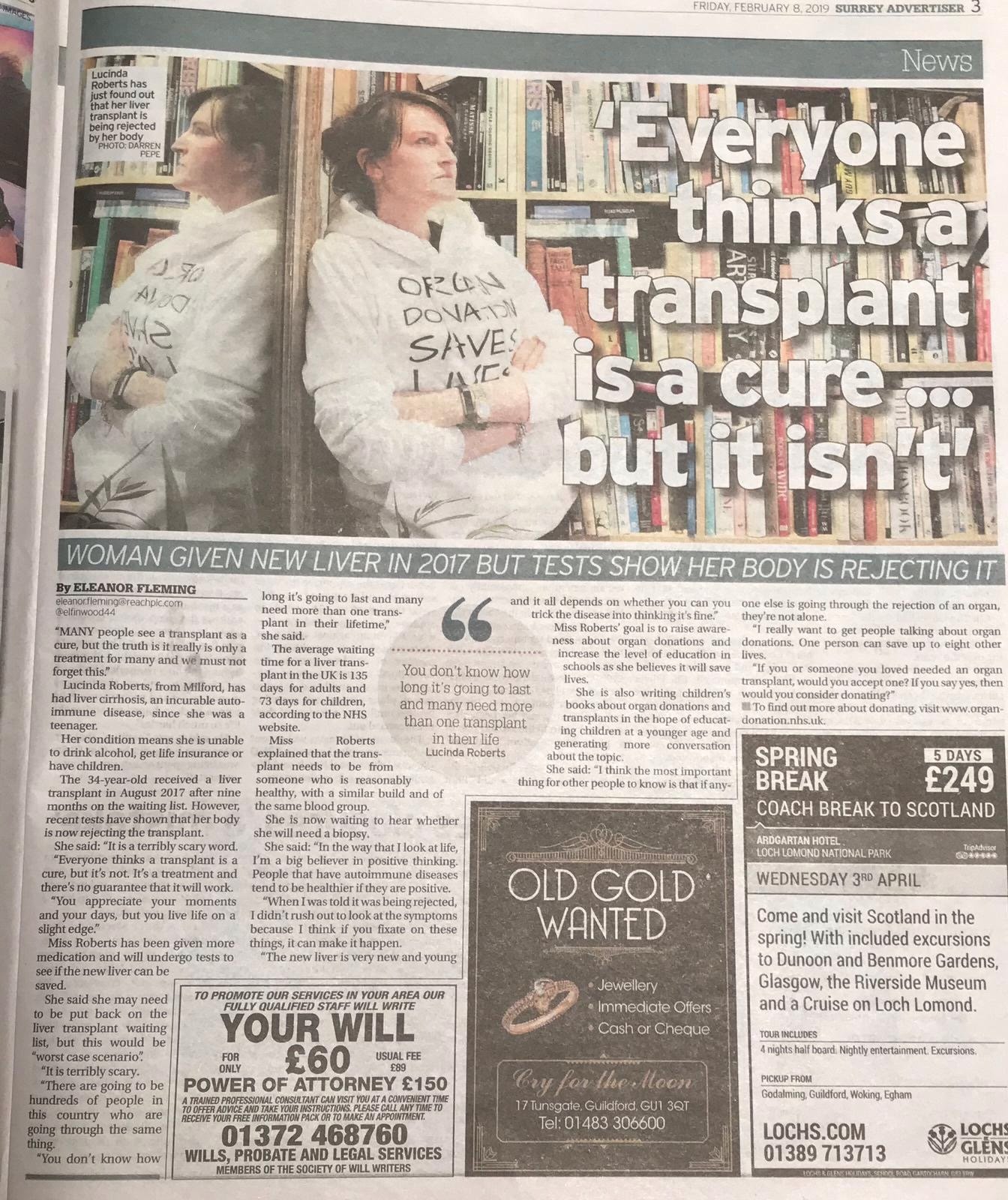 Photograph of a woman standing against a bookshelf with her arms crossed, wearing a white hoodie with handwritten text. The image is part of a newspaper article with a large overlay quote that reads, 'Everyone thinks a transplant is a cure... but it isn't.'