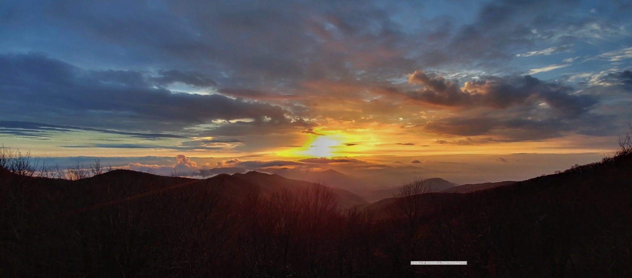 Sunset over mountain range with colorful clouds in the sky.