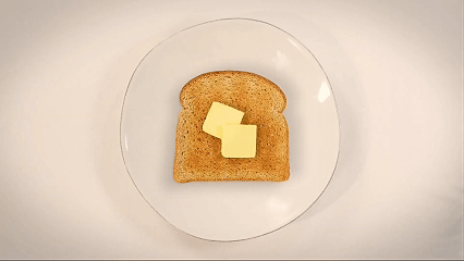 A slice of bread with two pats of butter on a clear glass plate.