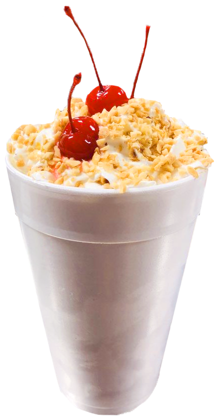A milkshake topped with whipped cream, chopped nuts, and maraschino cherries, served in a tall white cup.