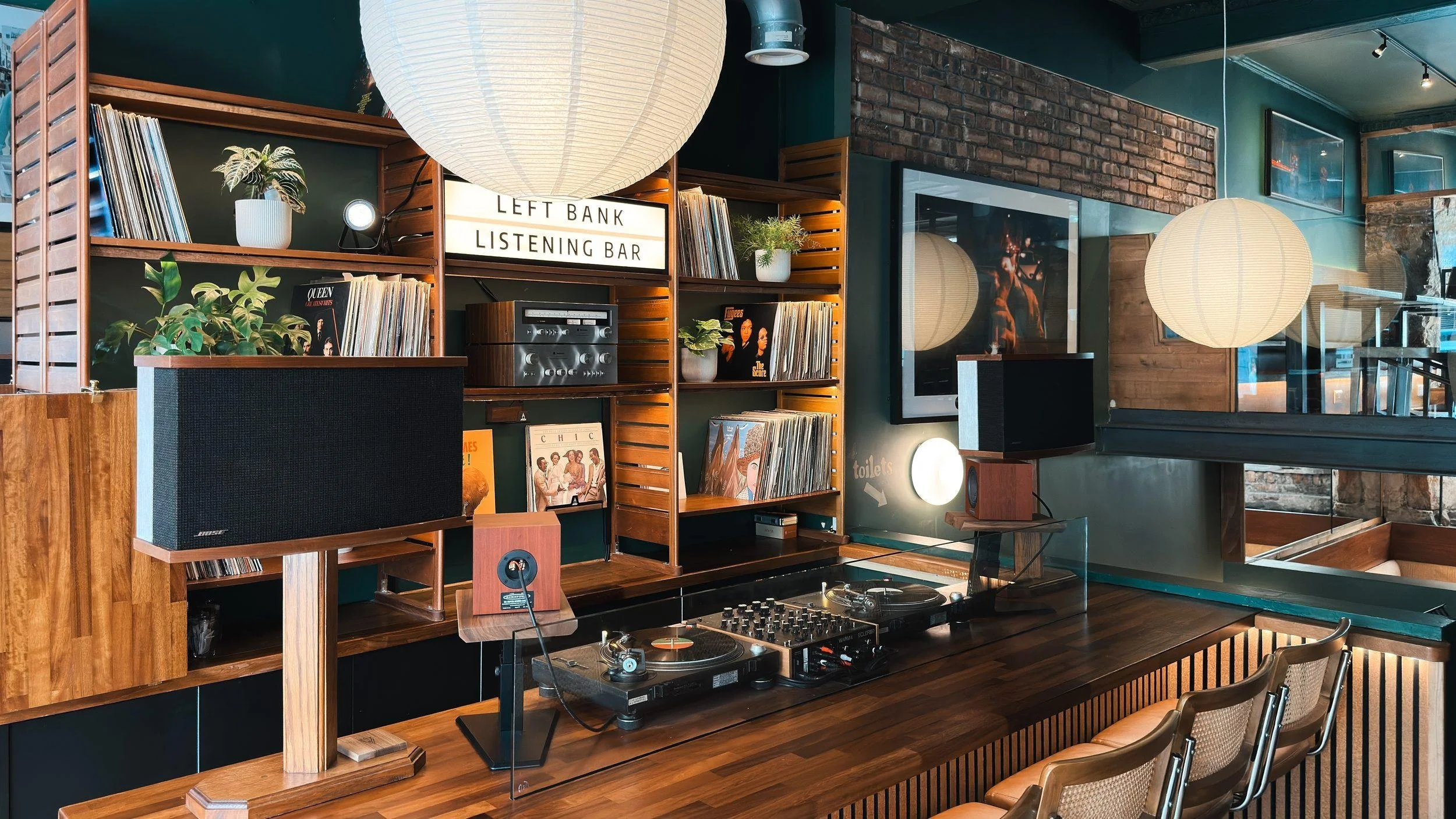 The listening bar from the side, with a vintage Bose 901, the vinyl decks, paper lanterns and stools along the counter.