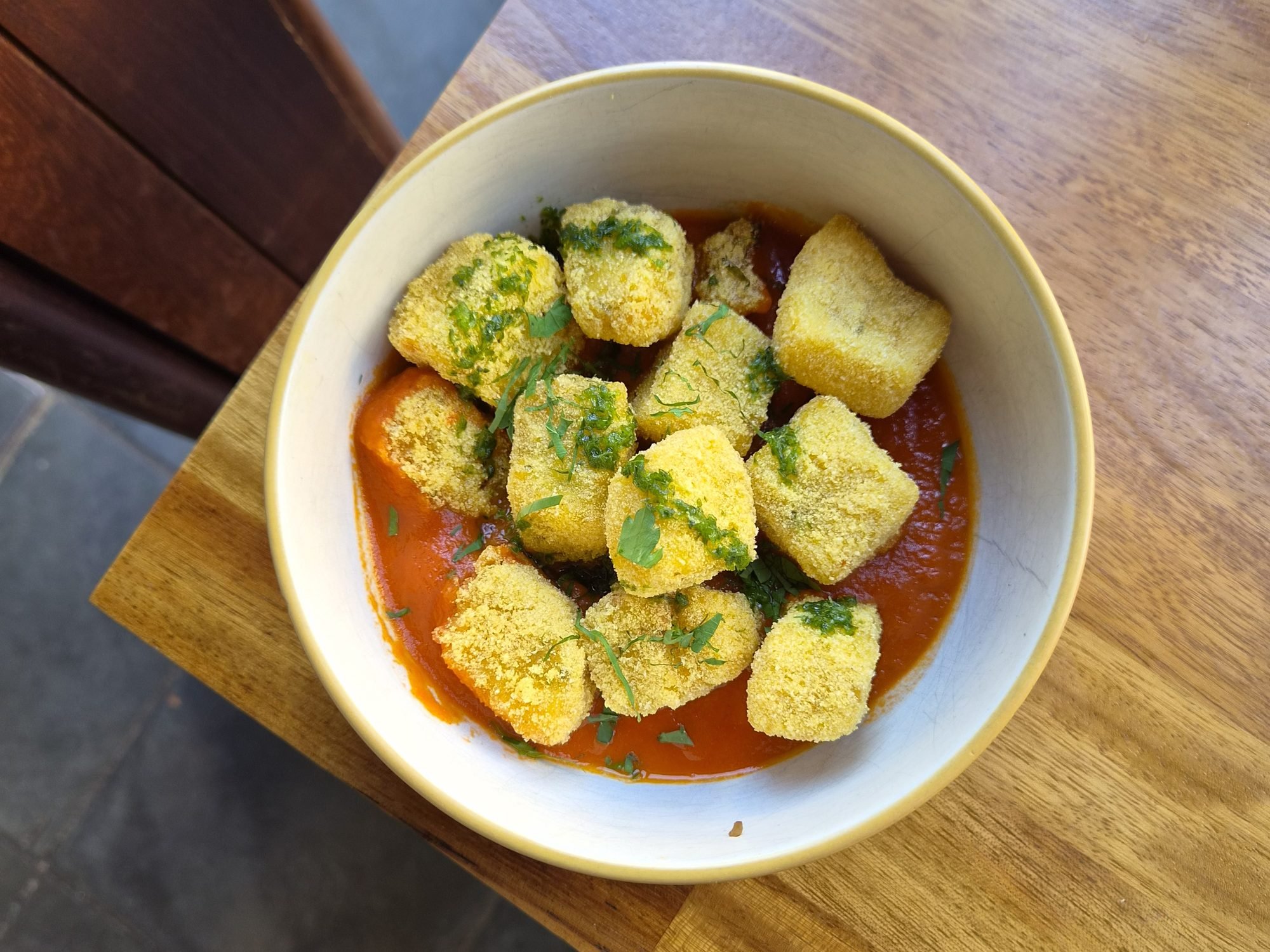 Crispy polenta cubes in tomato sugo with fresh herbs, on the vegan and gluten-free menus at The Left Bank.