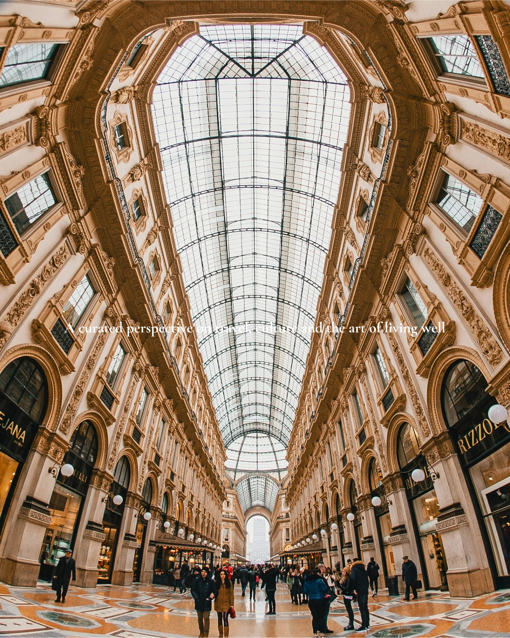 Interior of an elegant shopping arcade with high ornate ceilings and a glass skylight, filled with shoppers and storefronts on each side.