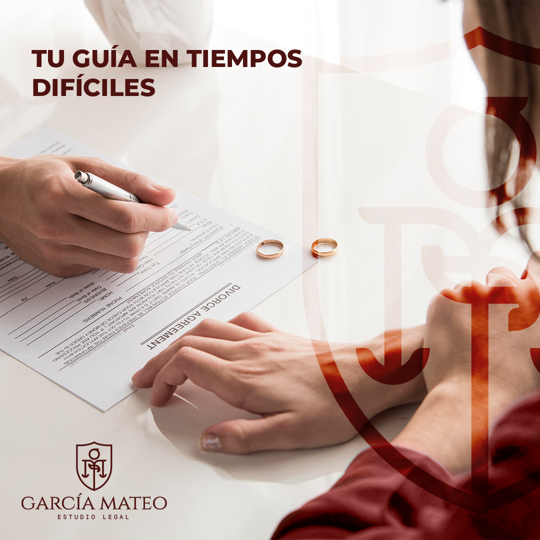 Persona firmando un acuerdo de divorcio mientras otra persona observa, con anillos de boda sobre la mesa, en un entorno claro y profesional.