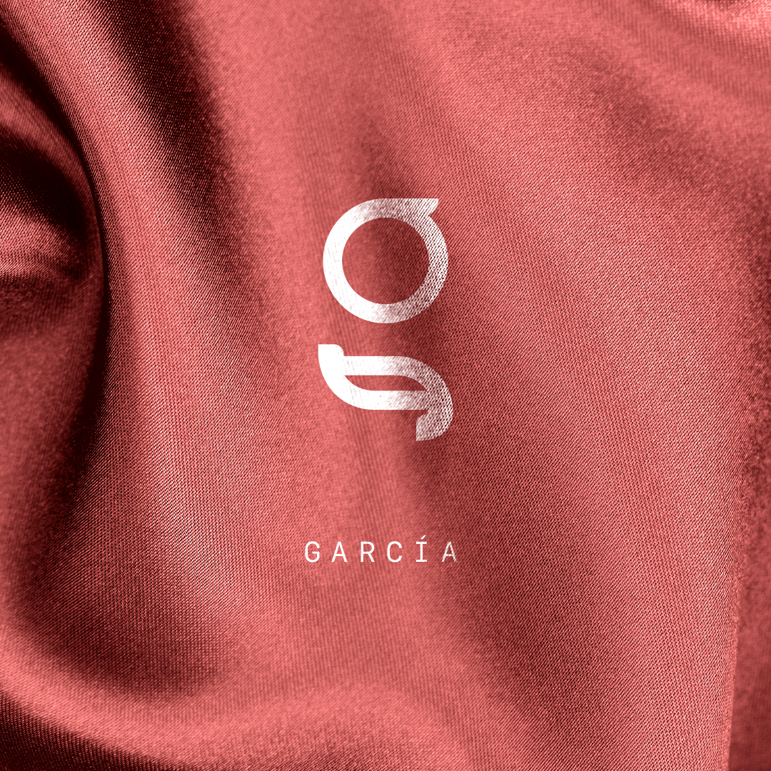 Fondo de tela de color rosa con el texto 'García' y un logotipo en blanco.