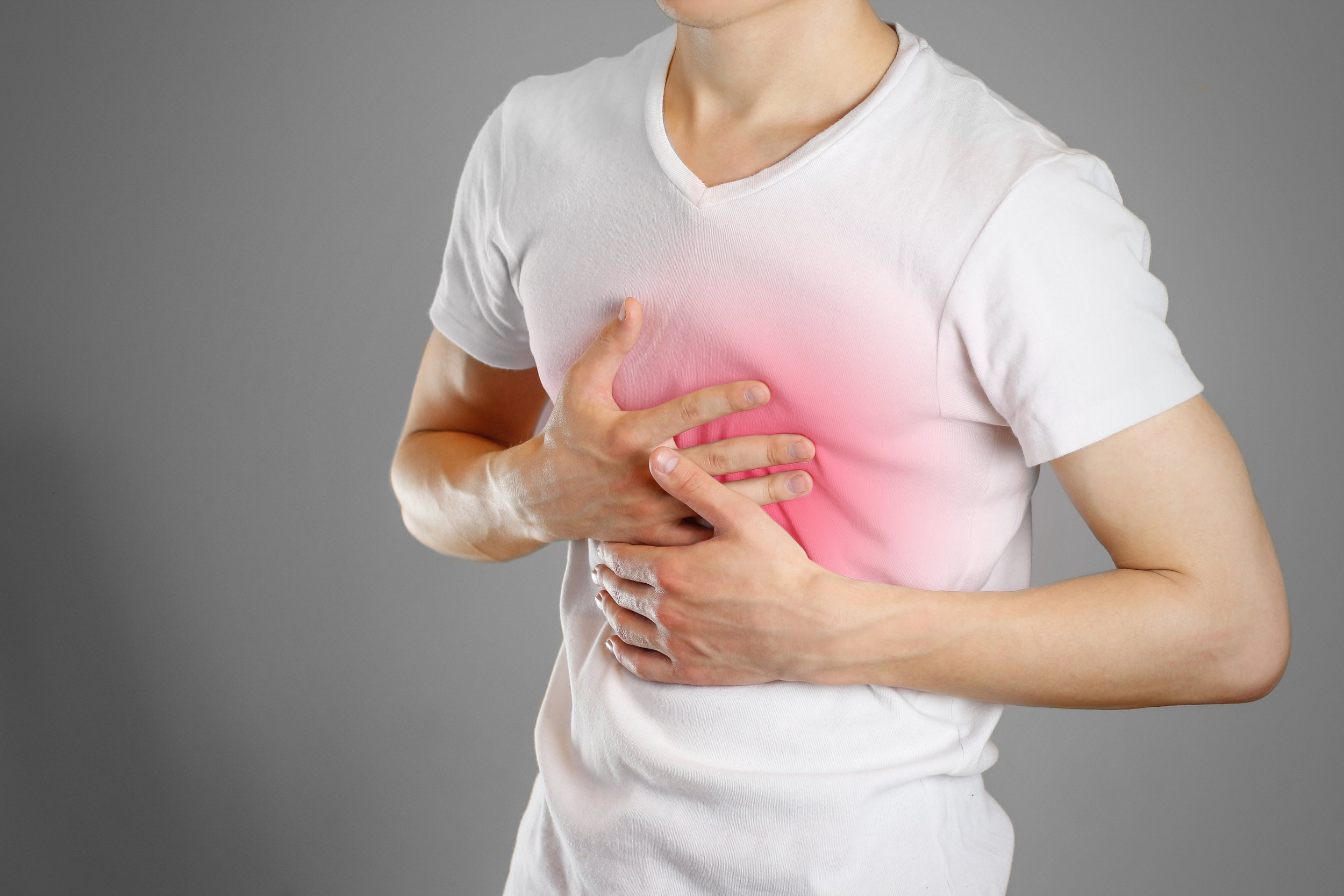 Person wearing a white T-shirt, clutching their chest with a pink-highlighted area indicating pain or discomfort.