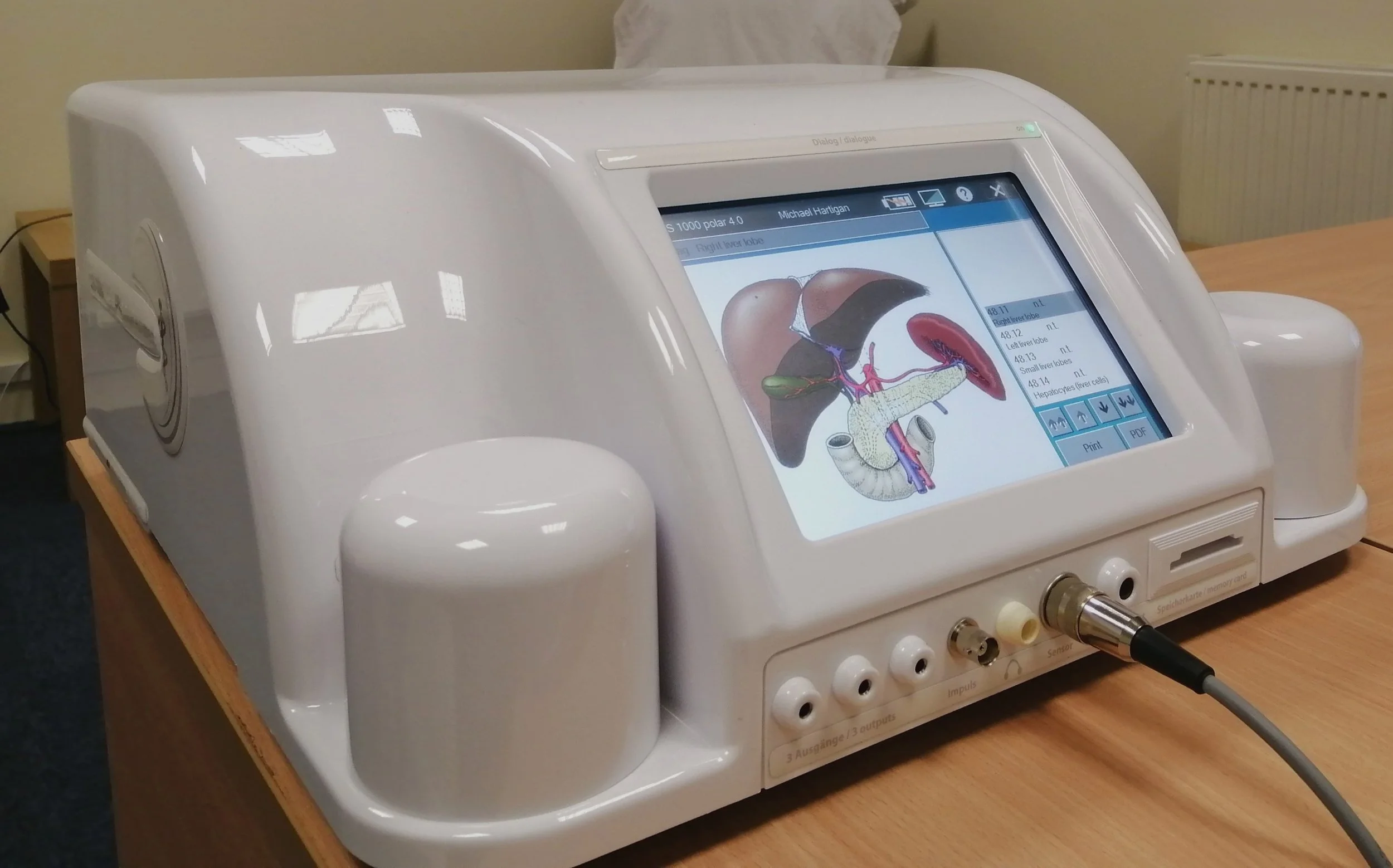 A medical imaging machine displaying an internal diagram of a human liver and surrounding organs on a digital screen.