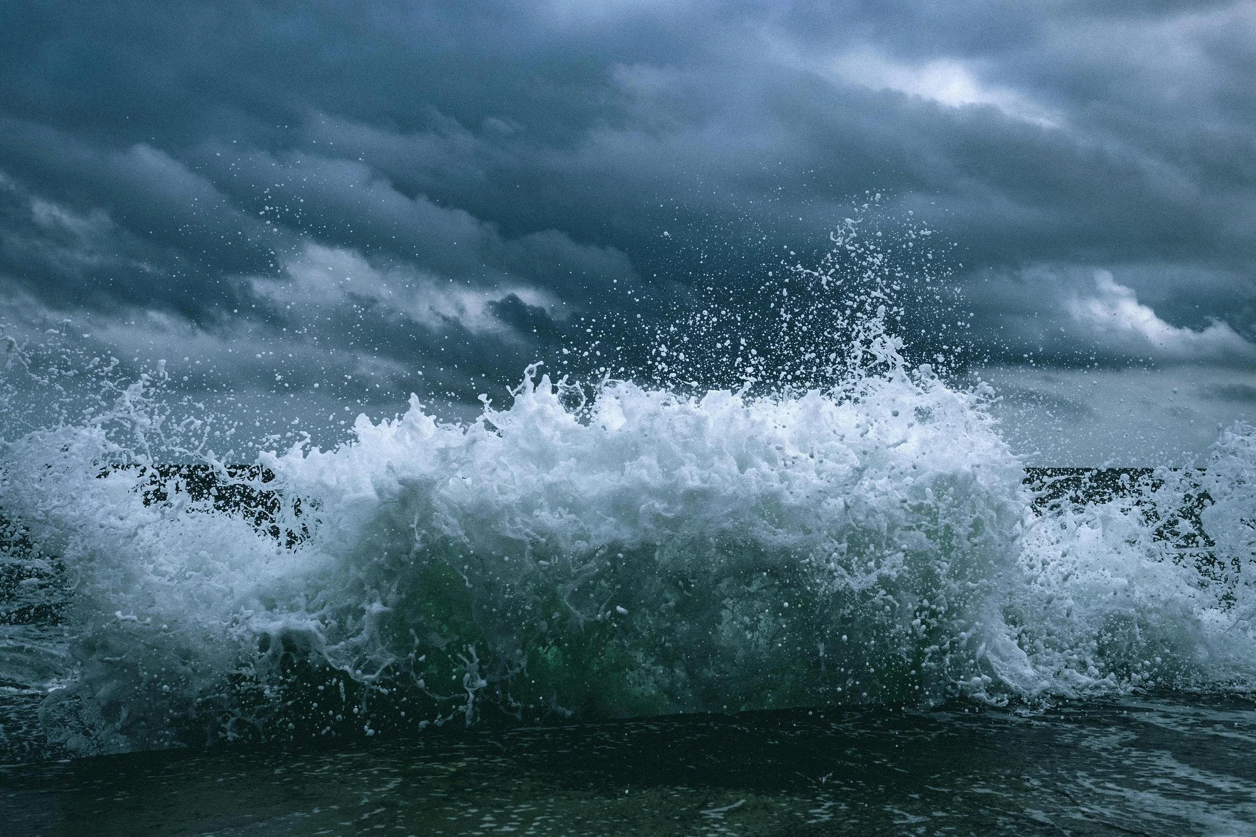 Rough ocean waves crashing under dark storm clouds.