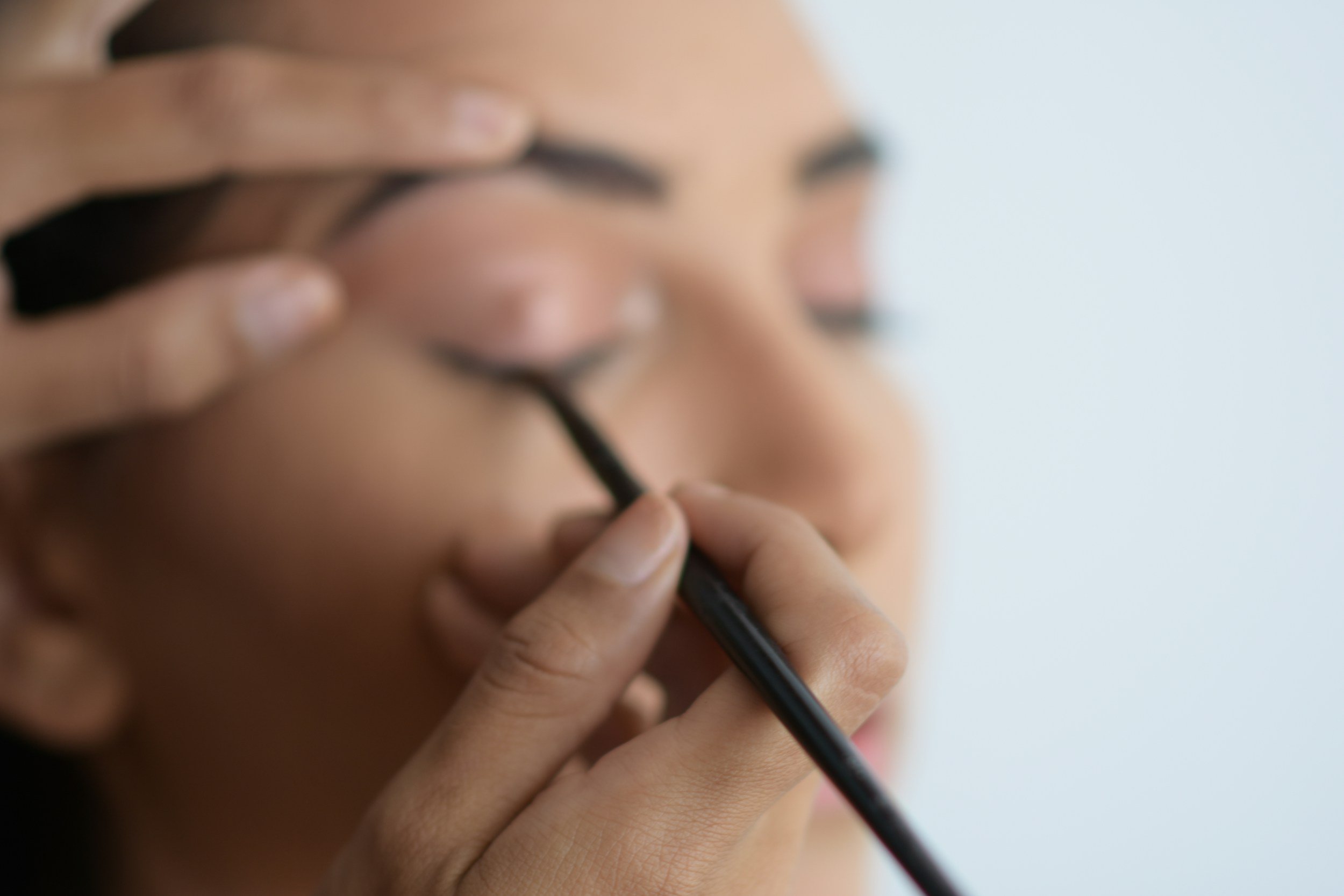 A person applying black eyeliner with a brush to their eyelid.