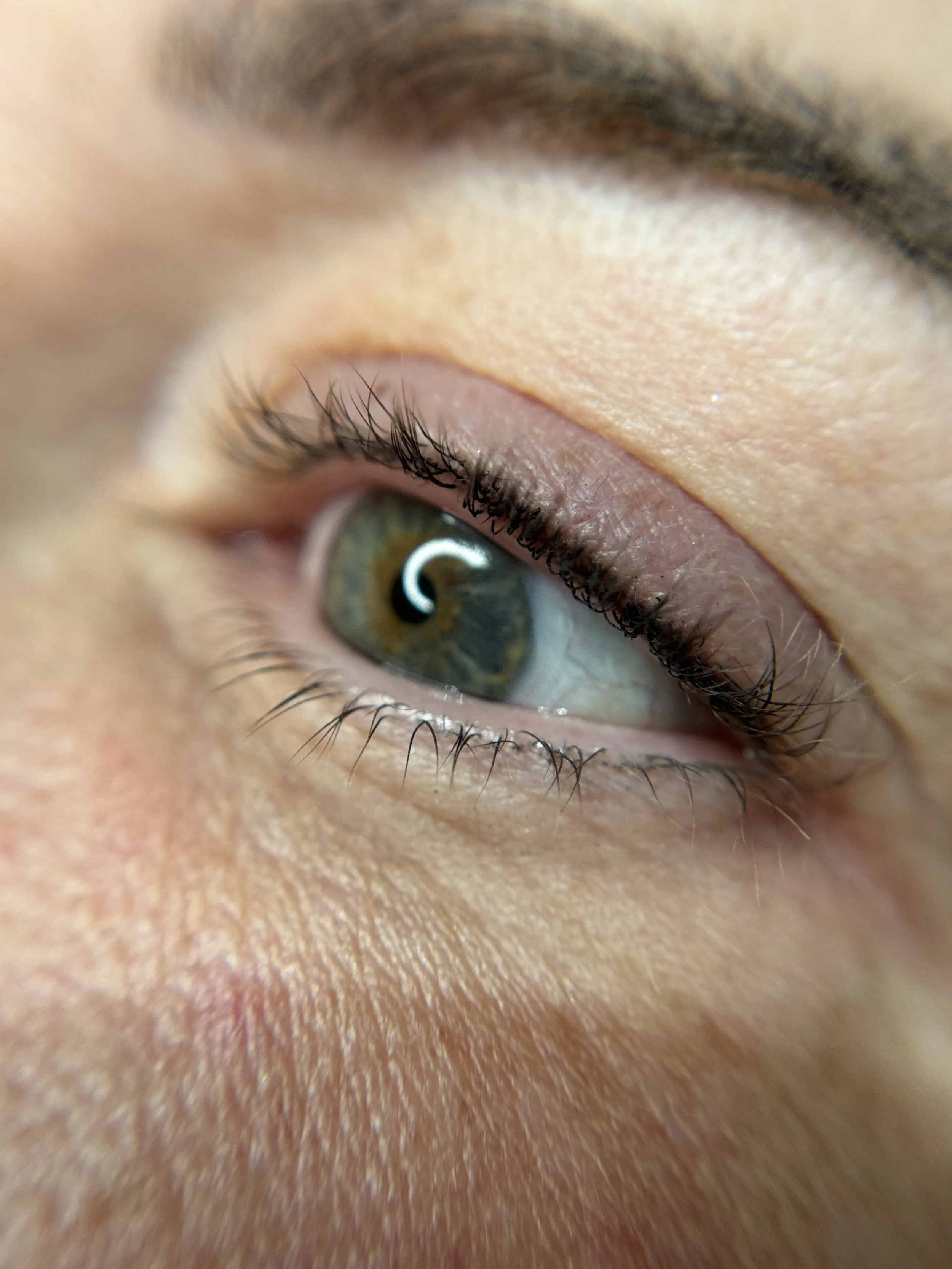 Close-up of a human eye with green and brown iris and eyeliner tattoo