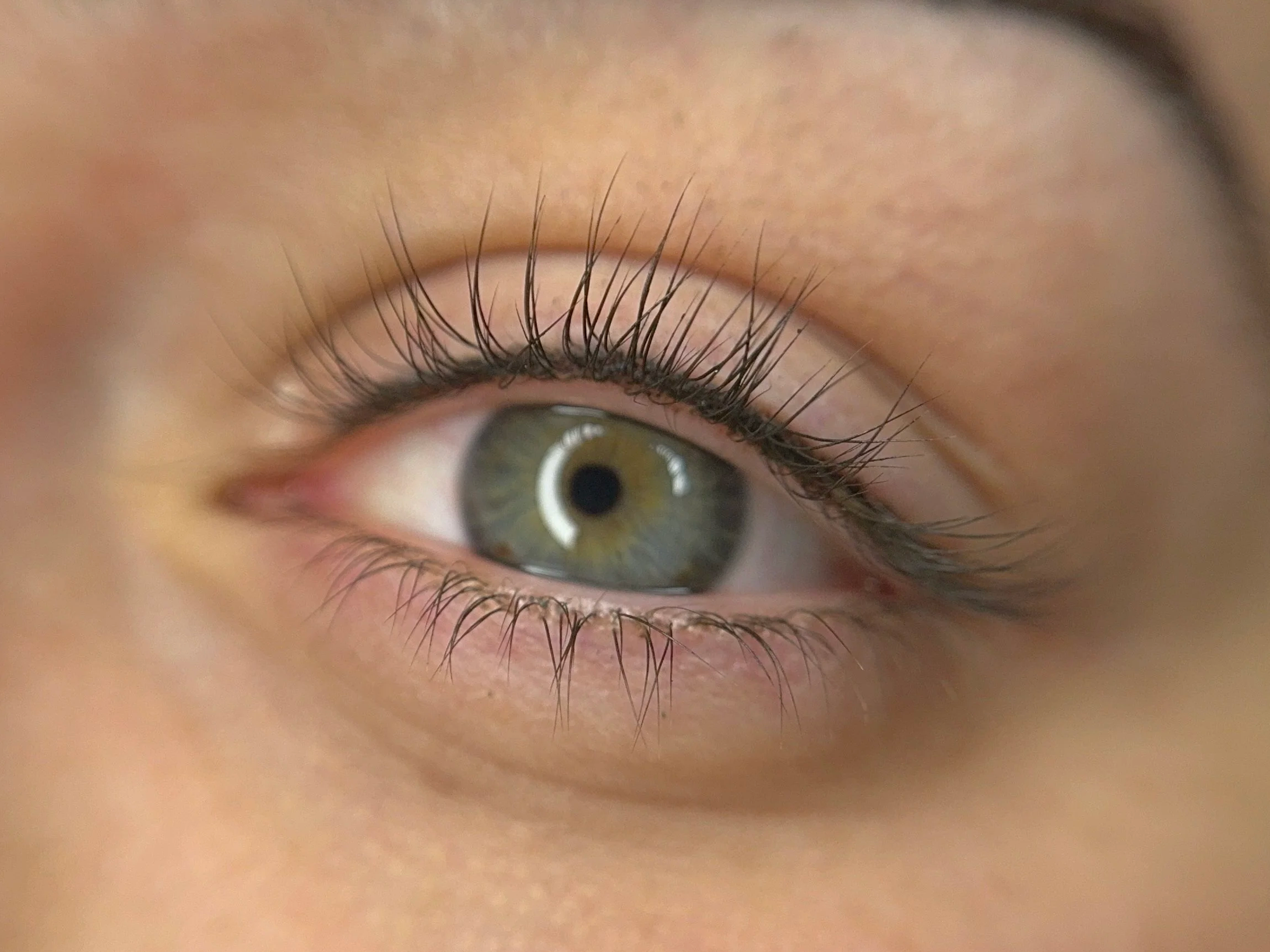 Close-up of a person's eye showing green iris, long eyelashes, and skin around the eye.