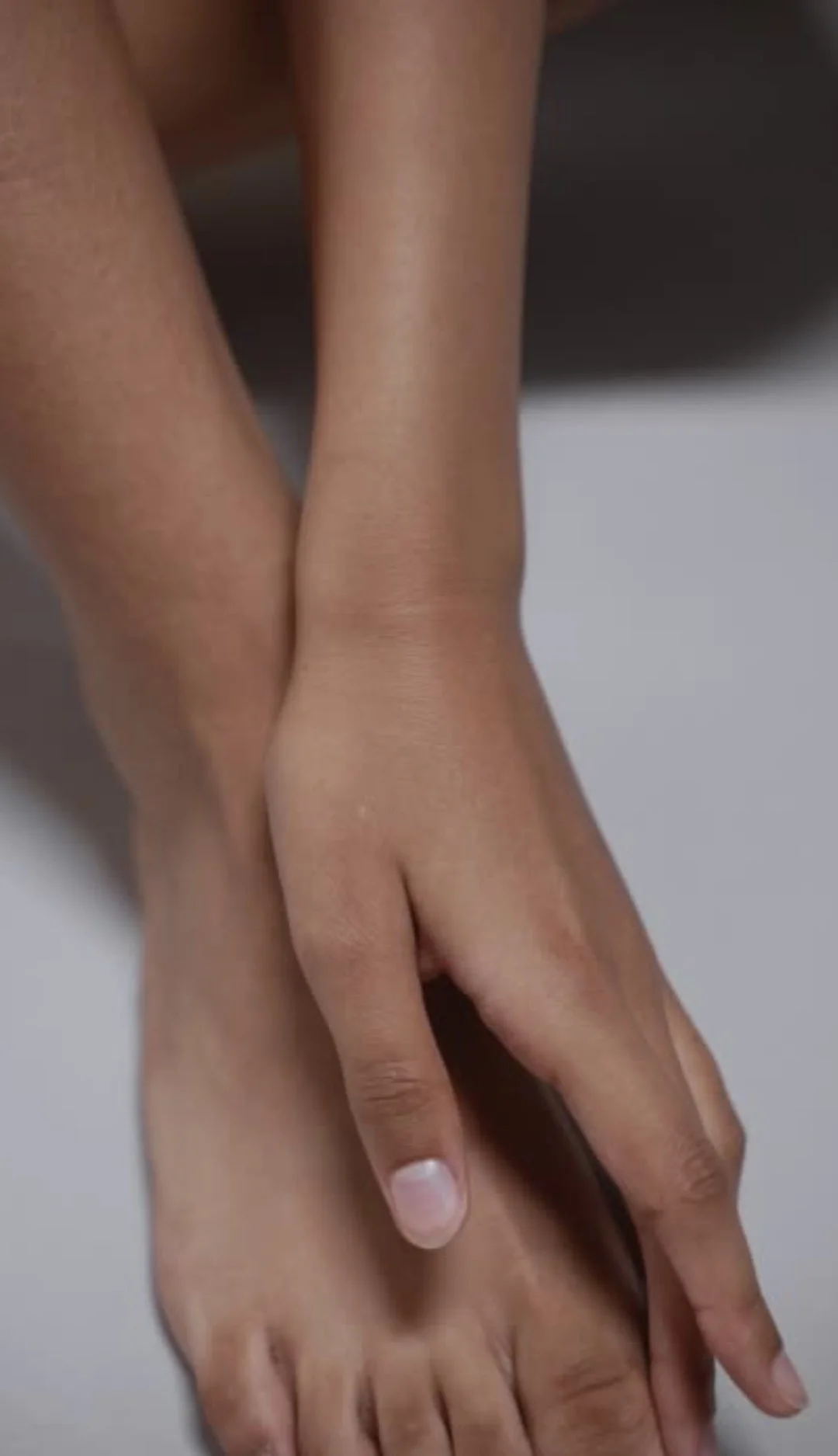 Close-up of two hands intertwined, showing fingers and palms, with a smooth background.