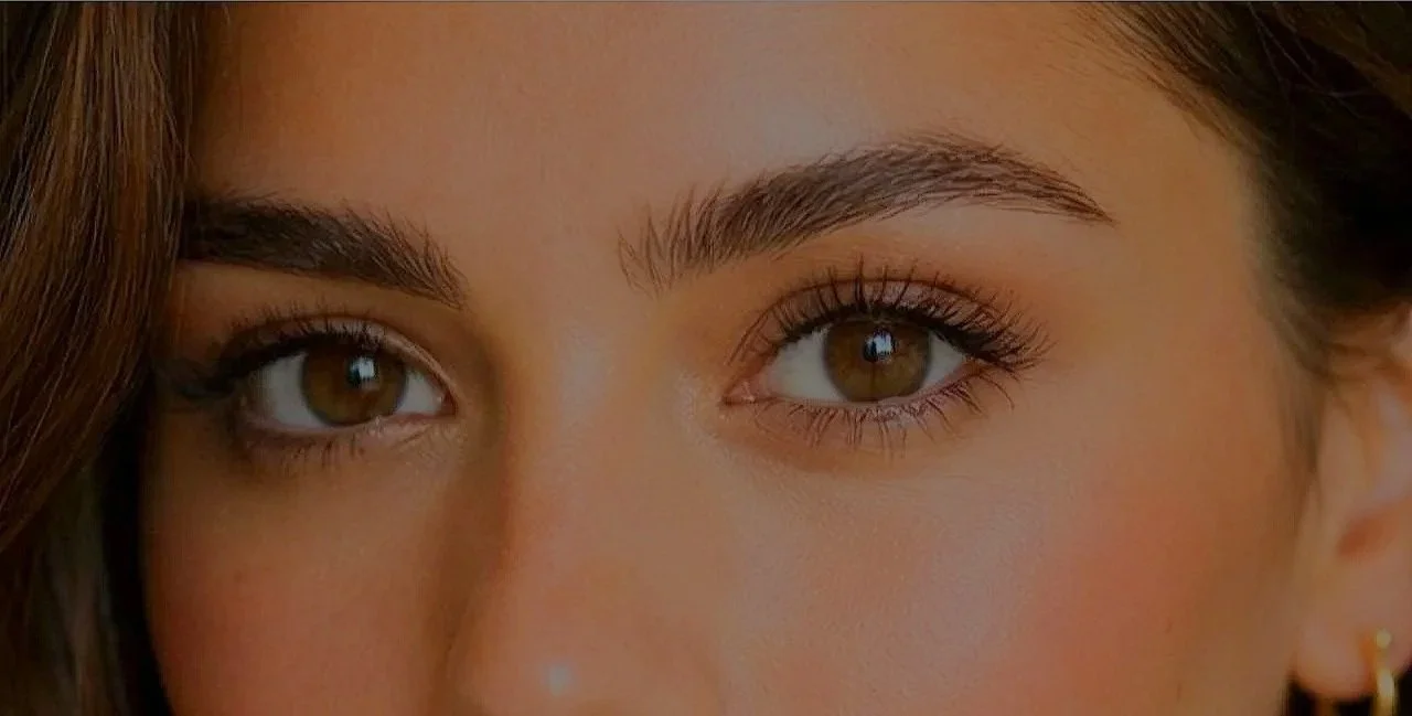 Close-up of a woman's eyes and eyebrows with makeup and long lashes.