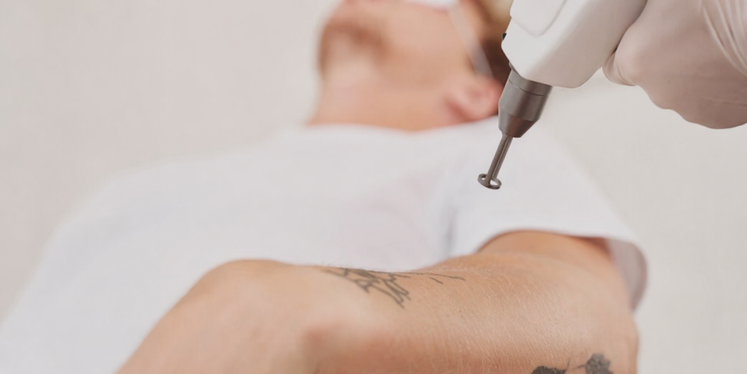A person receiving a tattoo on their arm from a tattoo artist using a tattoo machine.
