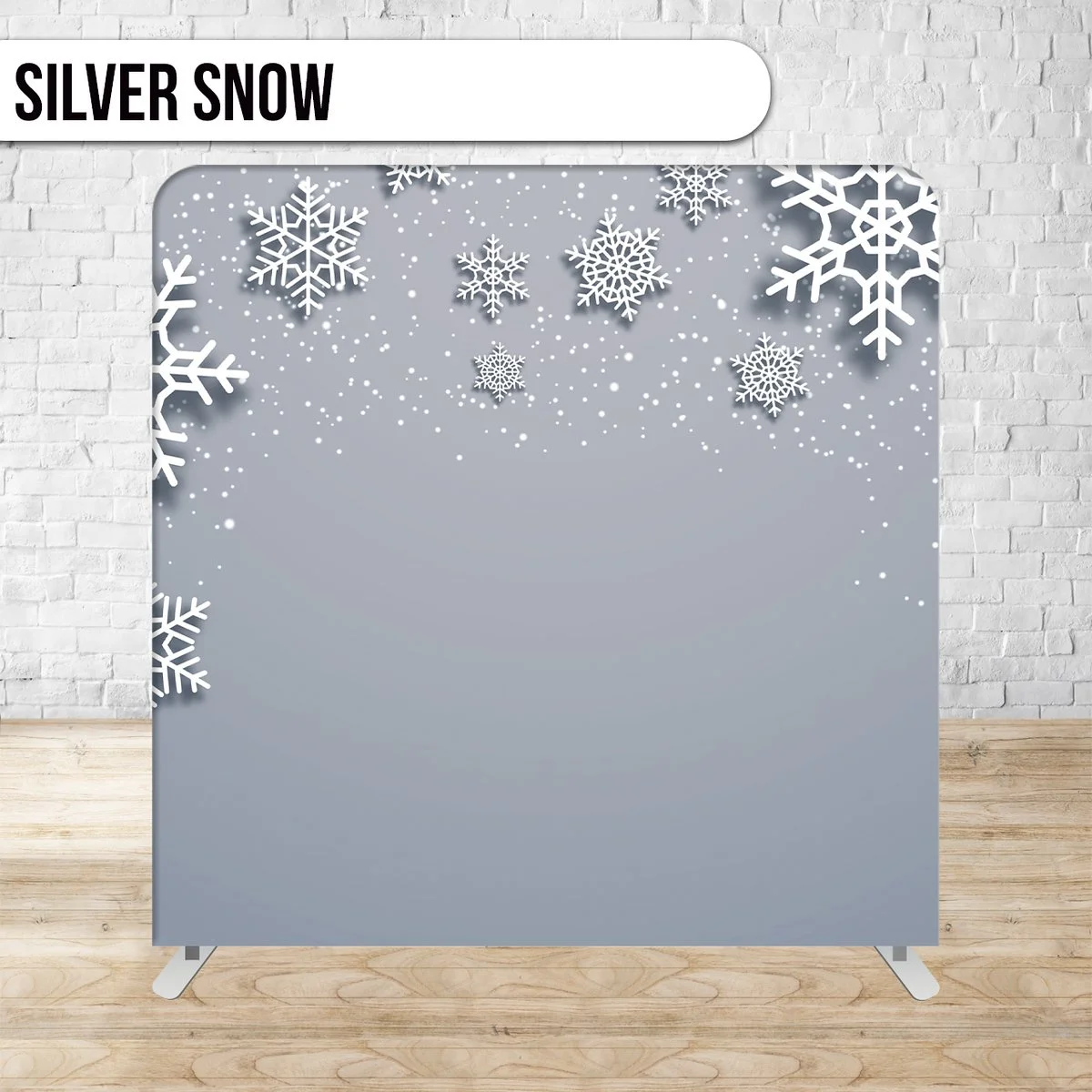 A decorative display with a snowy, winter theme featuring white snowflakes and small white dots on a gray background, set against a white brick wall.