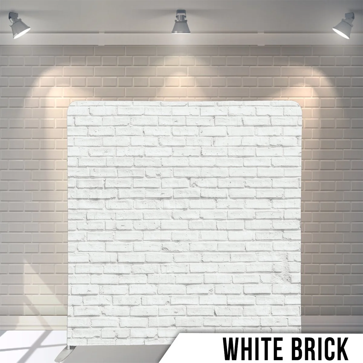 White brick wall illuminated by three ceiling spotlights in a room.
