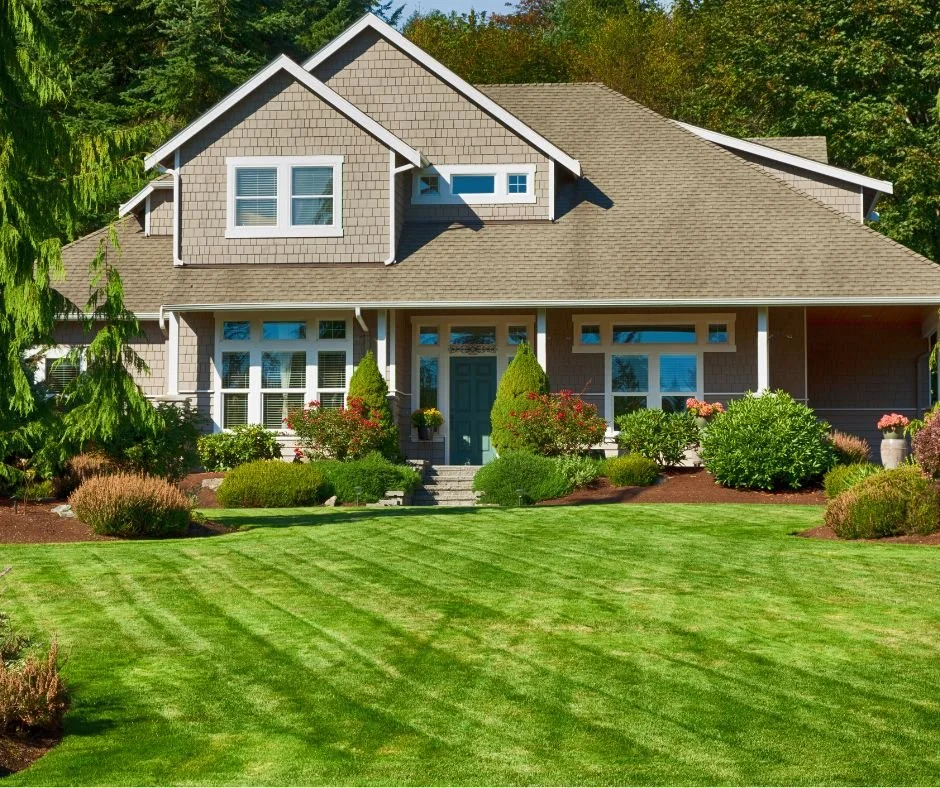 Front view of a two-story house with a well-maintained lawn, shrubs, and trees.