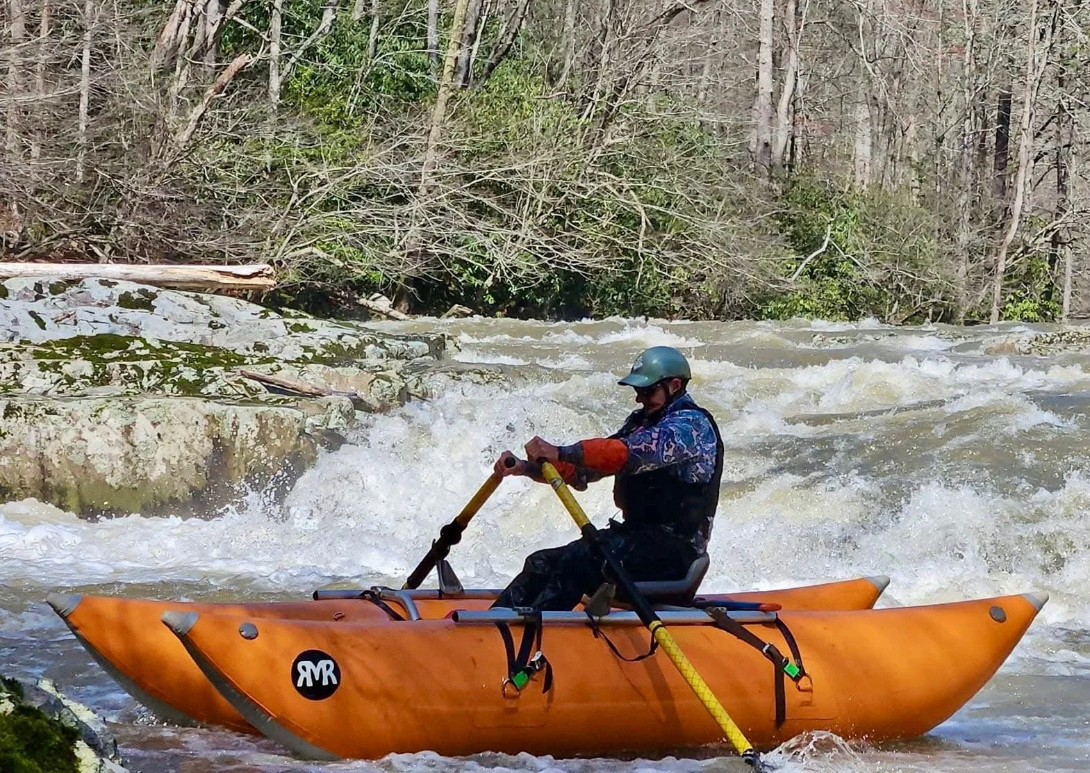 Person kayaking on fast-moving river surrounded by trees and rocks.