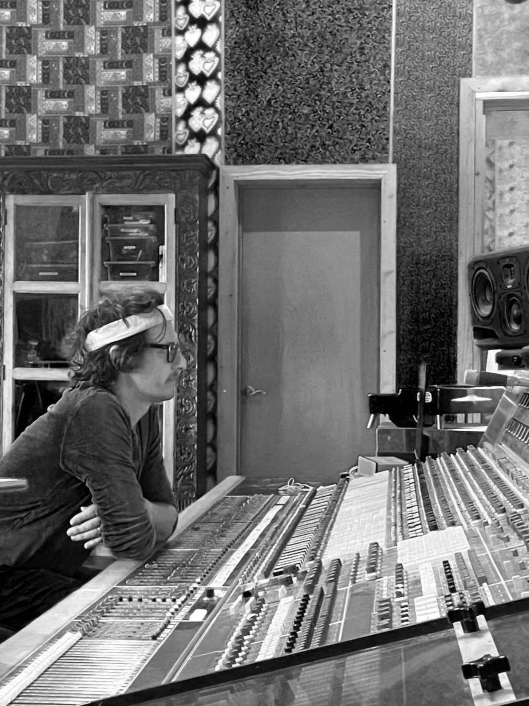 Scott Hirsch is sitting in a recording studio at a vintage Neve audio mixing console, looking intently at the equipment.