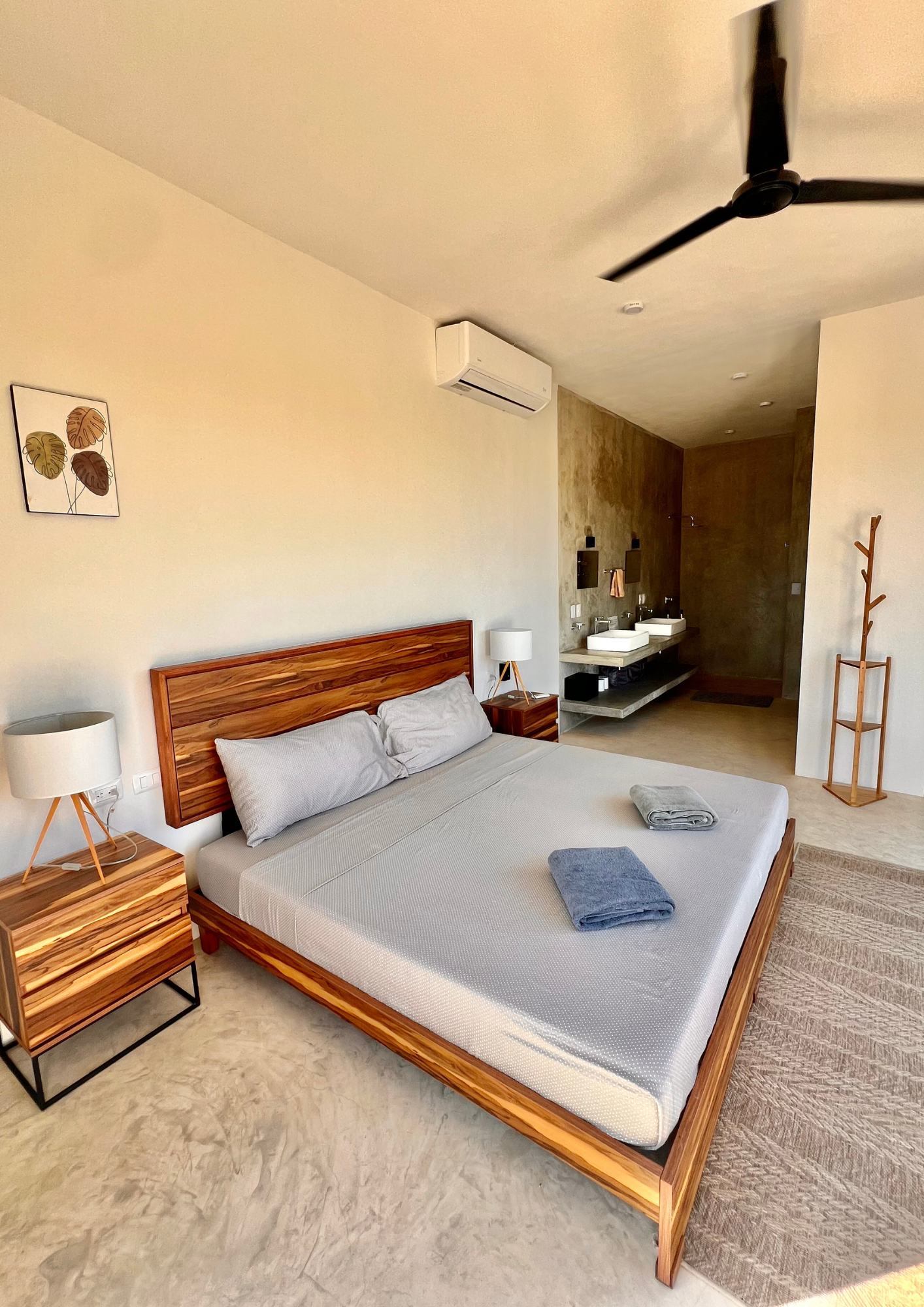 Chambre moderne avec lit en bois, deux lampes de chevet, toilette, lavabo, lavabo, miroirs, tapis beige, pièce lumineuse, décoration minimaliste.