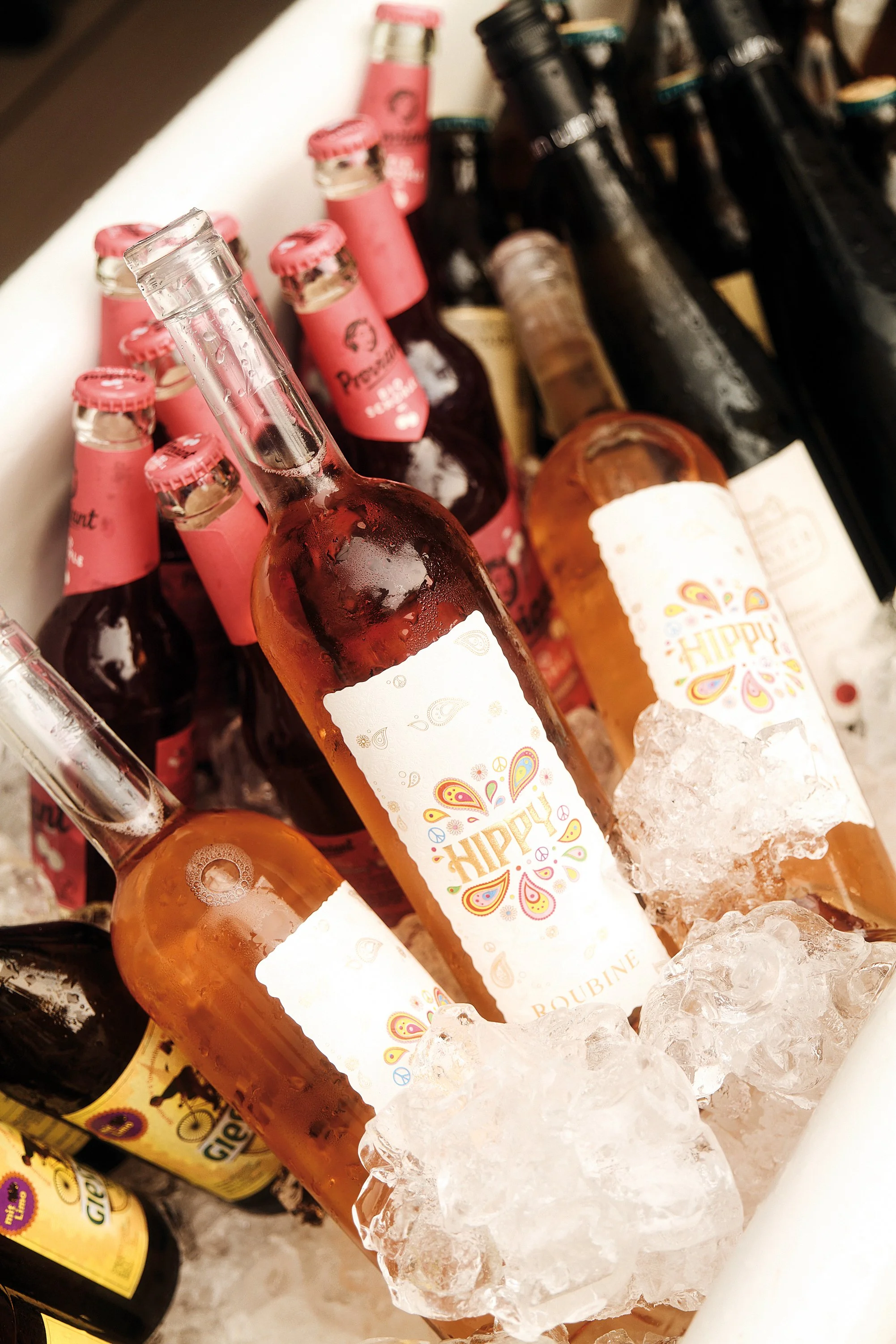 Flaschen von rosé und anderen alkoholischen Getränken in einem Eimer mit Eis, auf einem Tisch