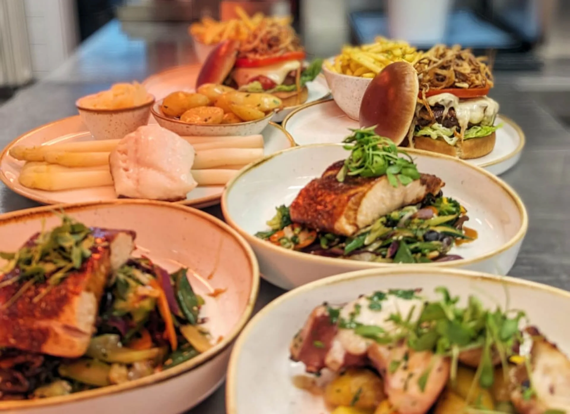 Verschiedene vorbereitete Gerichte wie Fisch, Fleisch, Beilagen und Sandwiches auf Tellern