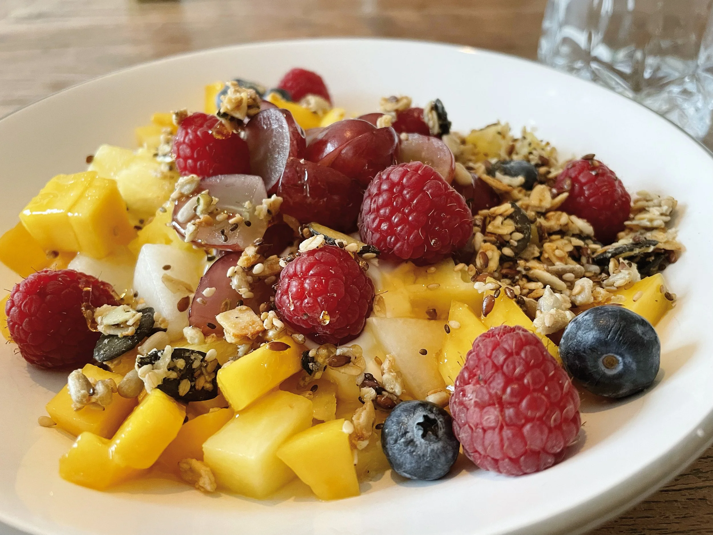 Obstsalat mit Heidelbeeren, Himbeeren, Mango, Honigmelone, Nüssen und Samen