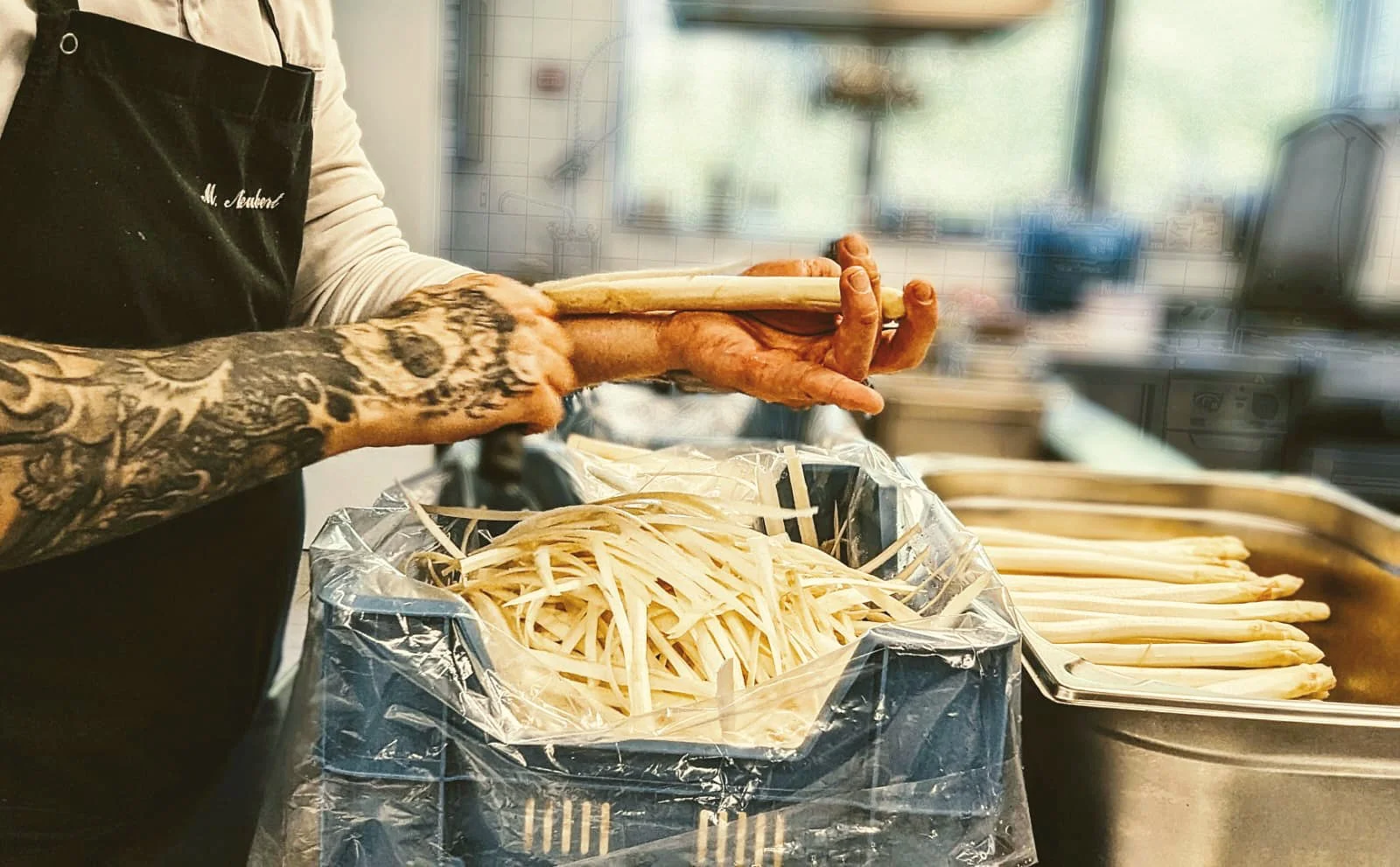 Person mit Tattoo-Armen hält eine Hummerzungen und legt sie in eine große Schüssel mit Zitronen. Im Hintergrund liegen weitere Zitronen.