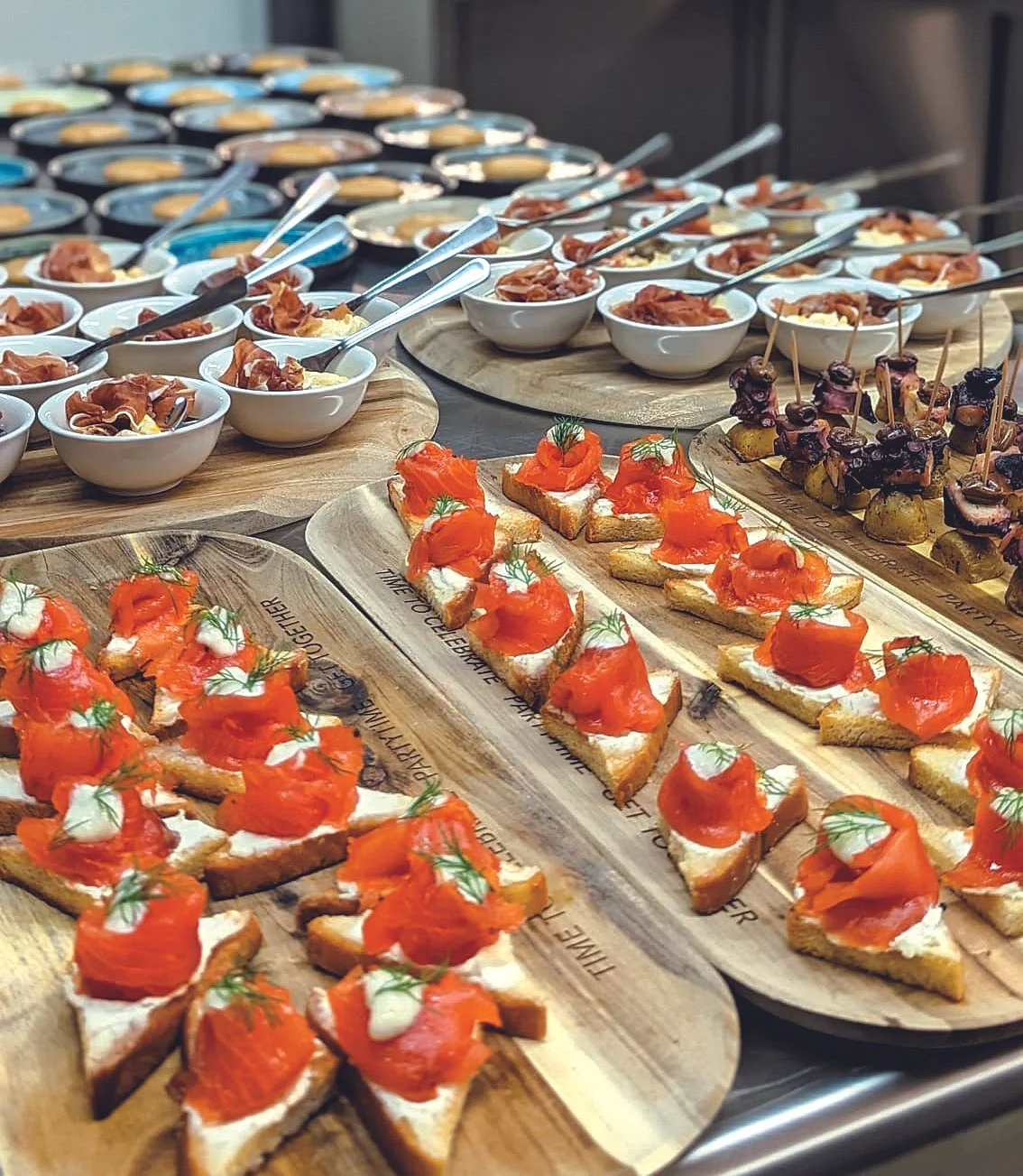 Verschiedene Canapés und Tapas auf Holzplatten bei einem Buffet.