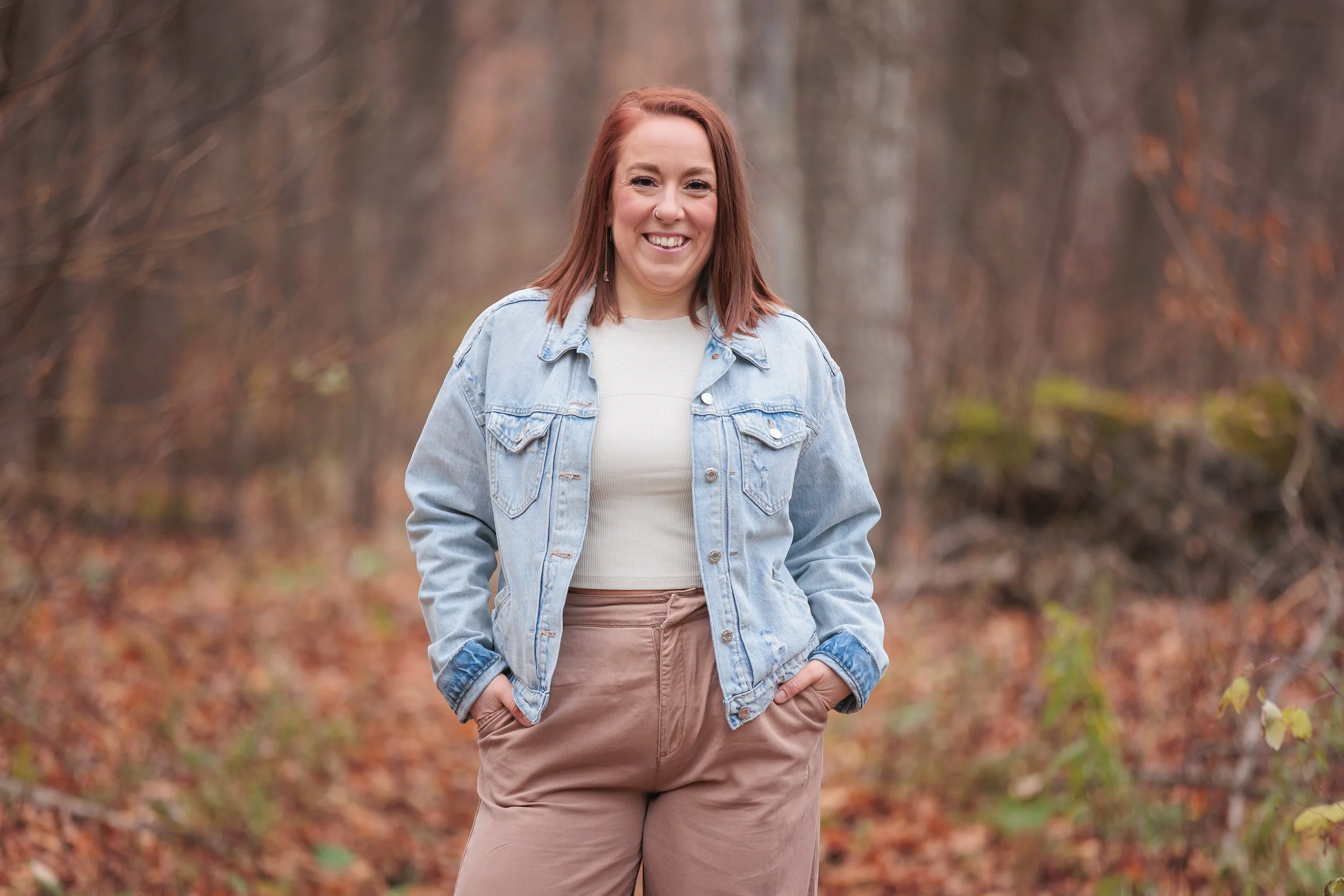 female makeup artist with red hair, light complexion, standing outside posing for a headshot