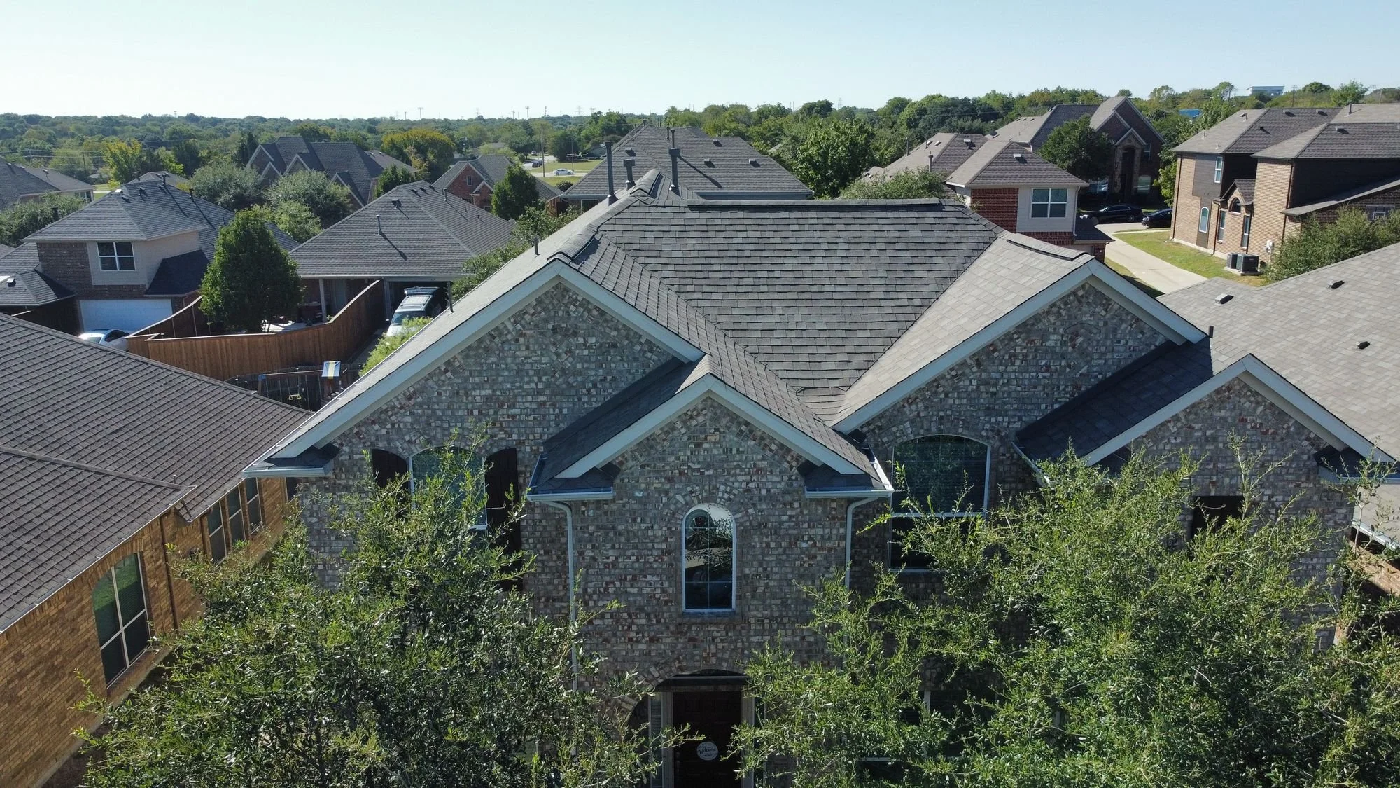 Aerial view of a stone home with a new shingle roof by Christian Brothers Roofing in North Texas