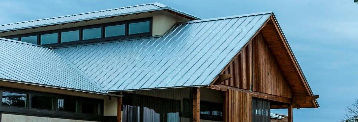 Modern house with metal roof, large windows, and wood accents.